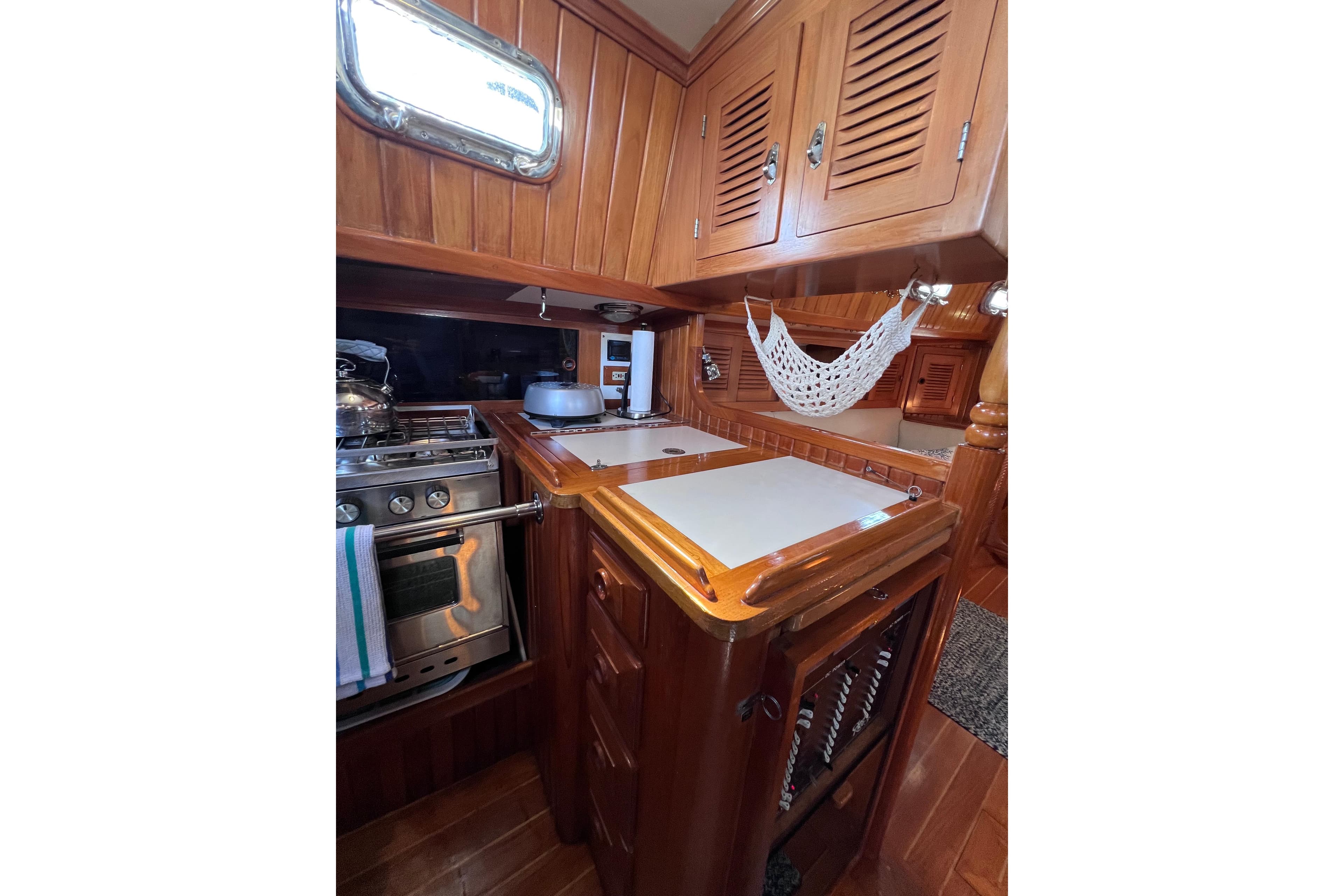 Cozy 1990 Cabo Rico 38R yacht galley with wooden cabinetry and compact stove.