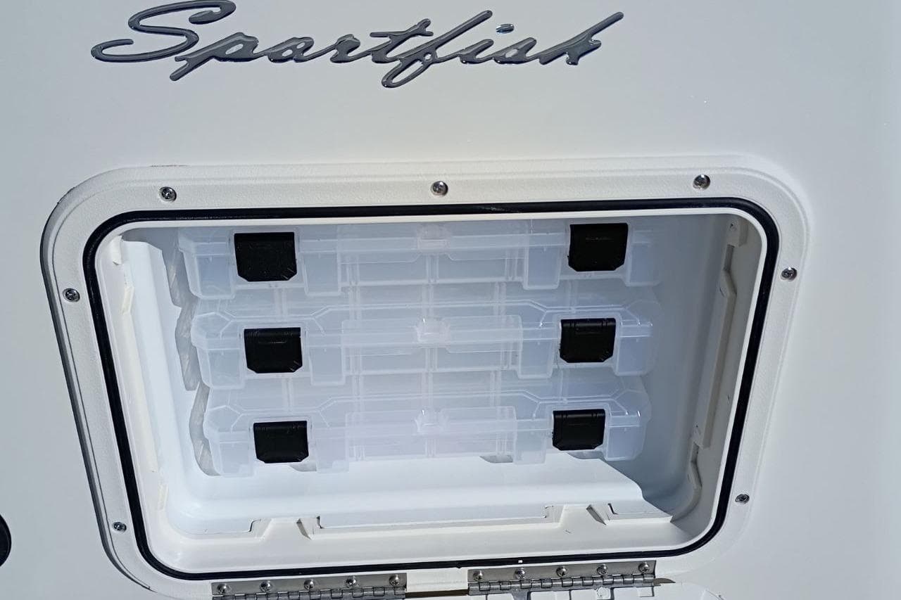 Pioneer 180 Sportfish 2026 tackle storage compartment with clear plastic boxes.