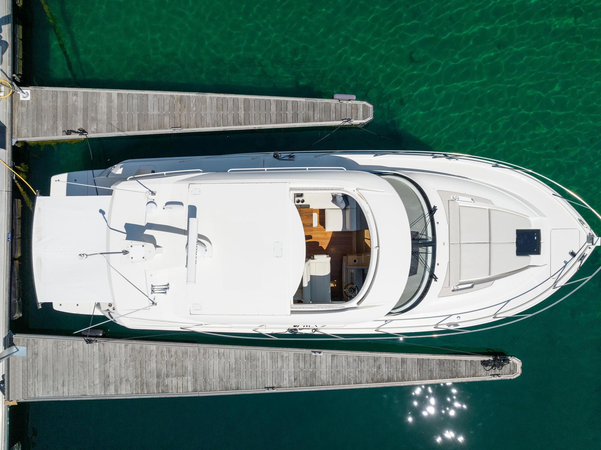 2022 Tiara Yachts C49 Coupe docked, aerial view, clear green water.