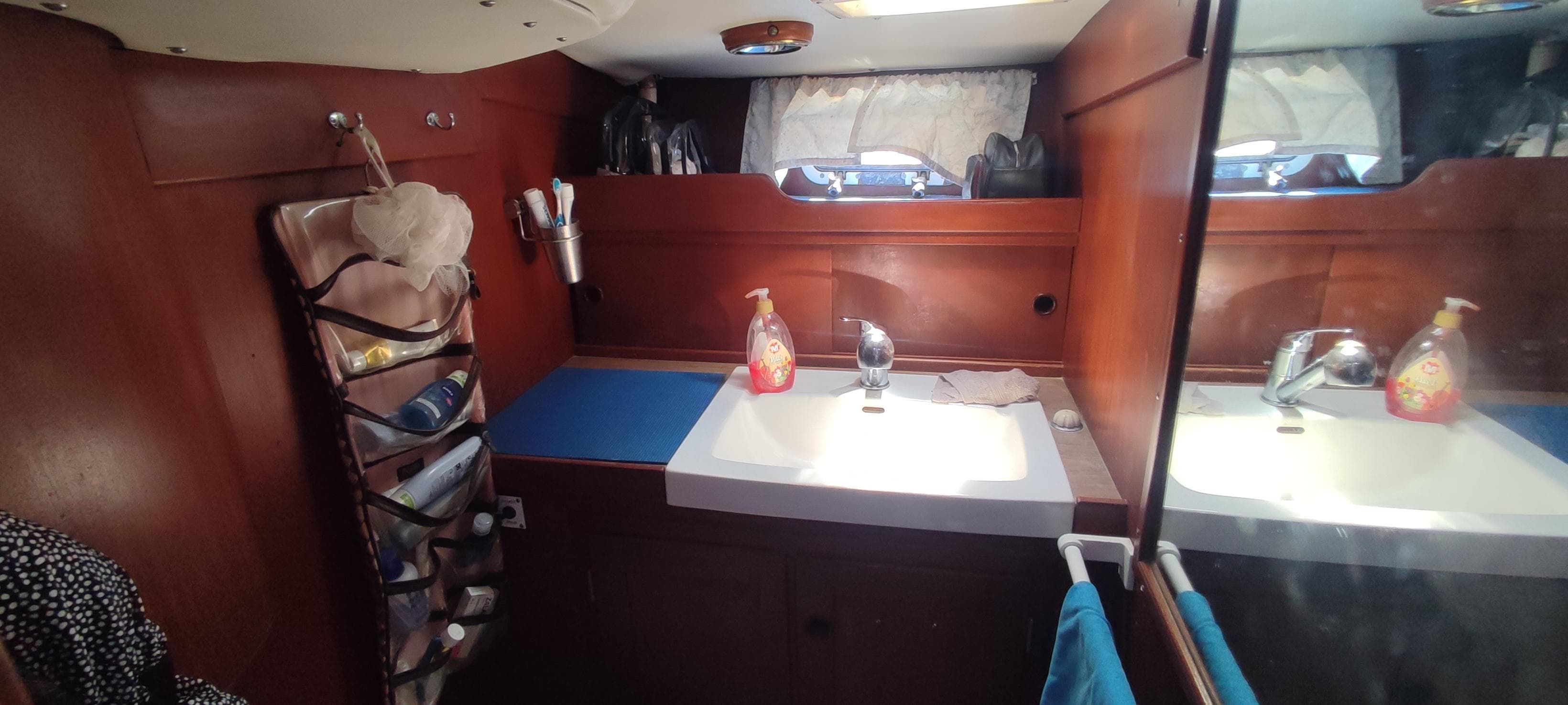 Interior of 1982 Hallberg-Rassy 42E yacht bathroom with sink, mirror, and storage.