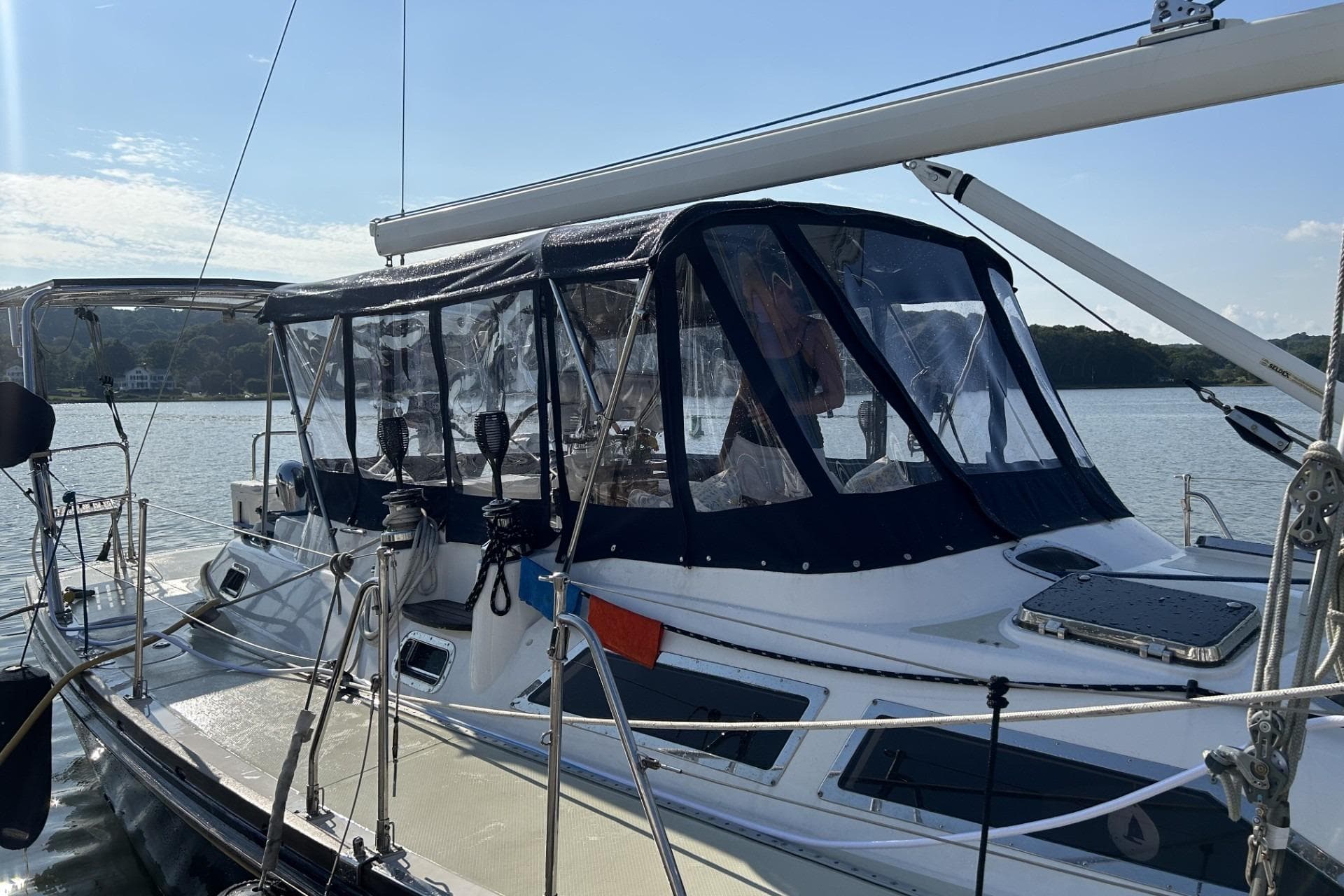 Sailing yacht Hylas 46, 2002 model, docked with protective canopy, on calm water.
