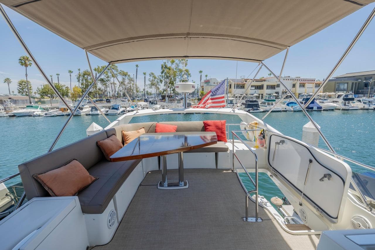 Luxurious 2015 Prestige 500FB yacht with spacious deck, seating, and marina view.