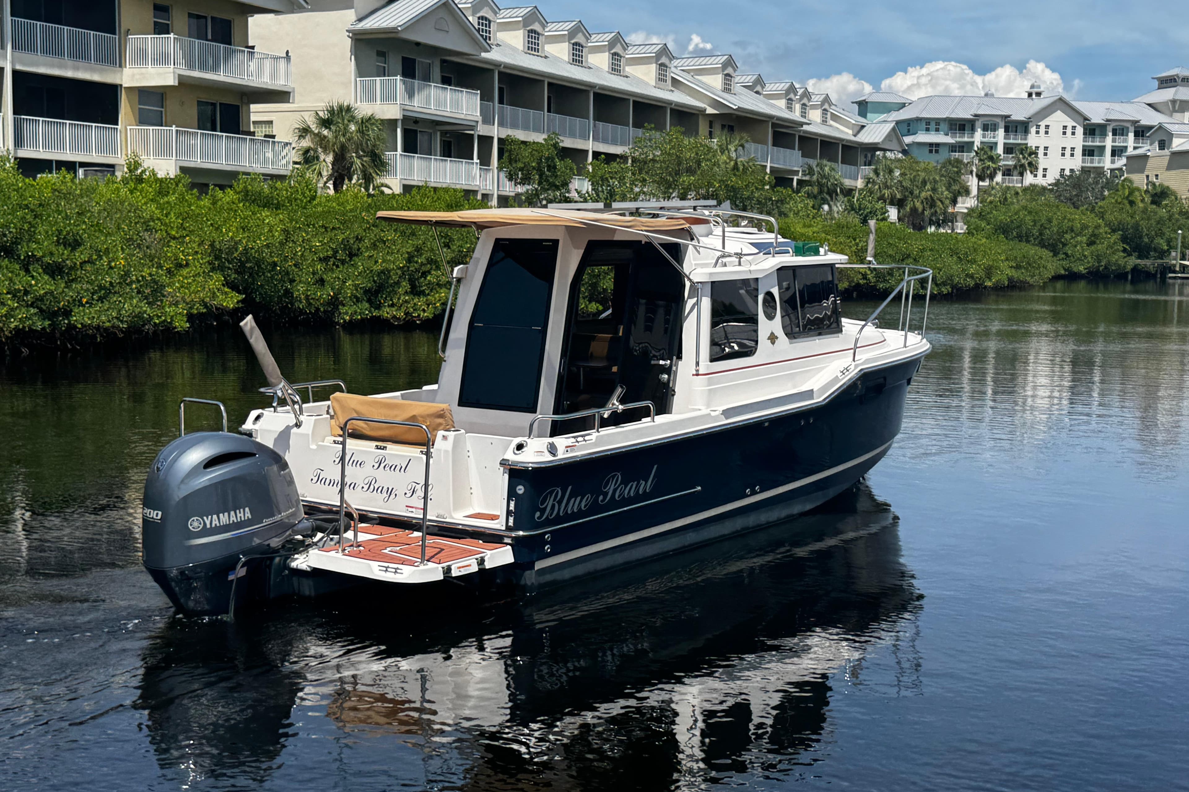 2023 Ranger Tugs R-23 boat on calm water near residential buildings.