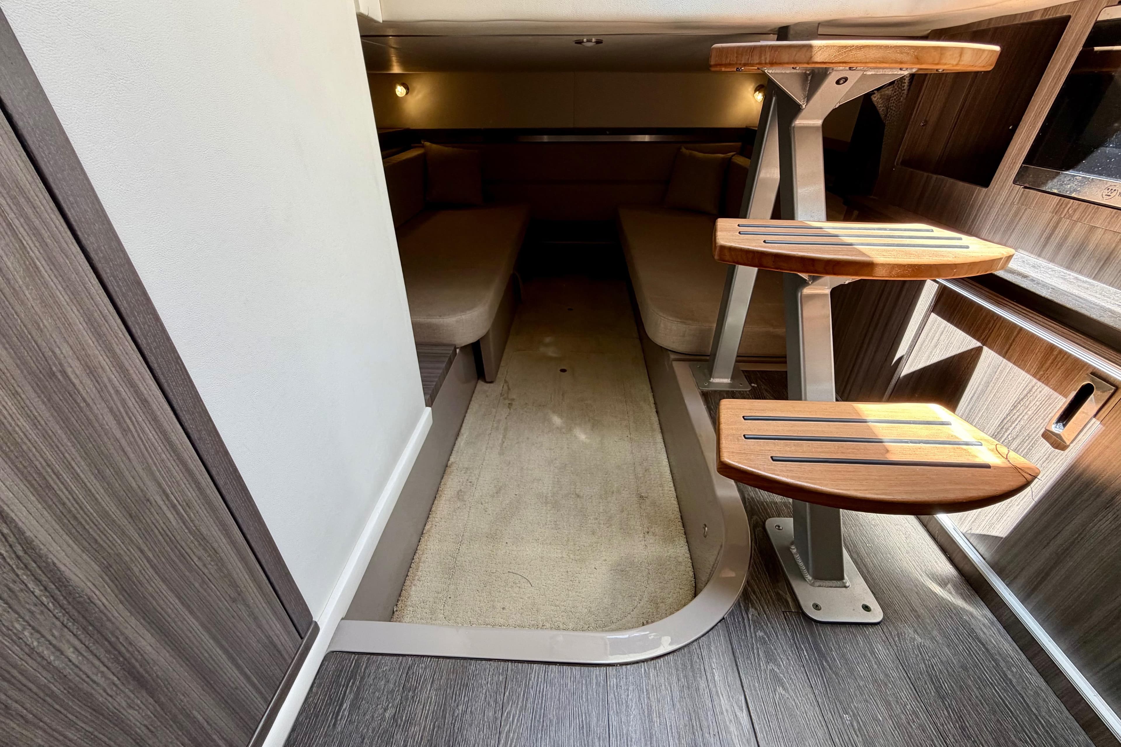 Interior cabin of 2019 Sea Ray Sundancer 320 with wooden steps and cozy seating.