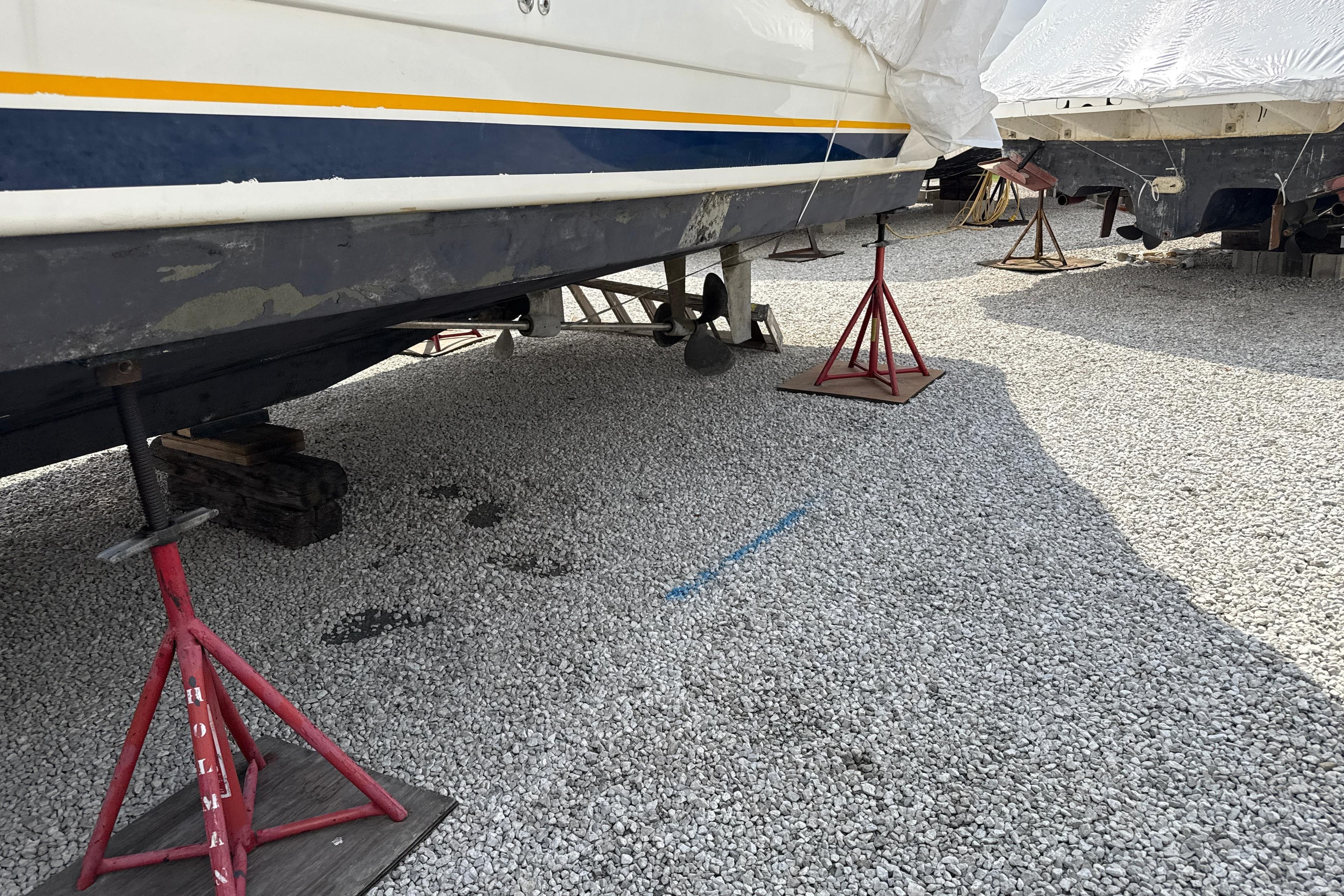 1999 Silverton 422 Motor Yacht on stands for maintenance in a gravel yard.