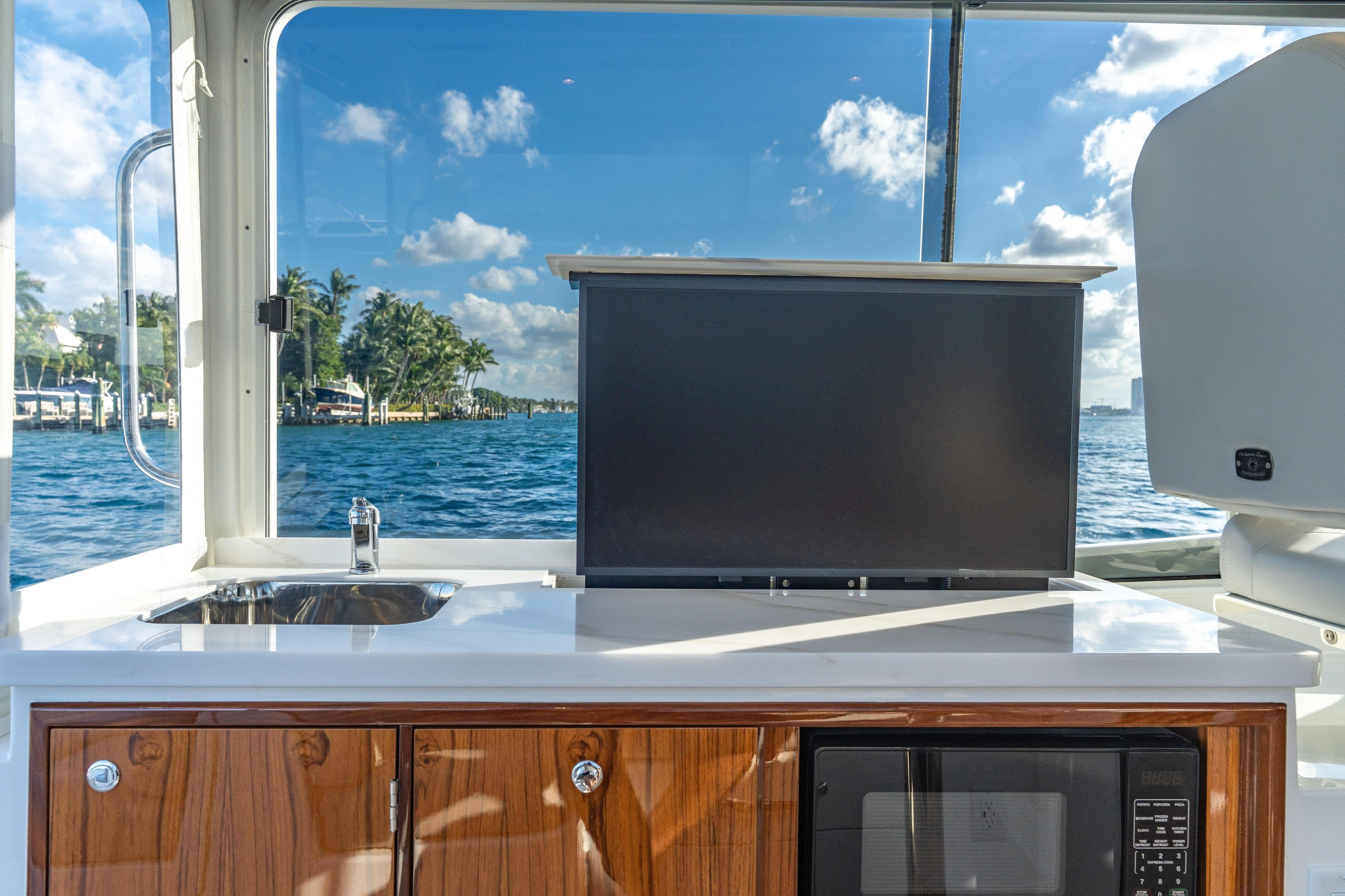 Interior of 2026 MJM 38RS yacht with sink, TV, and microwave, overlooking ocean.