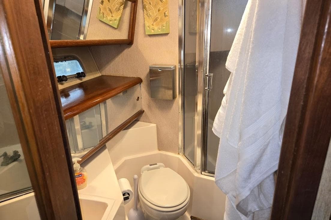 1987 Bayliner 4550 Motoryacht bathroom with shower, toilet, and wooden shelves.
