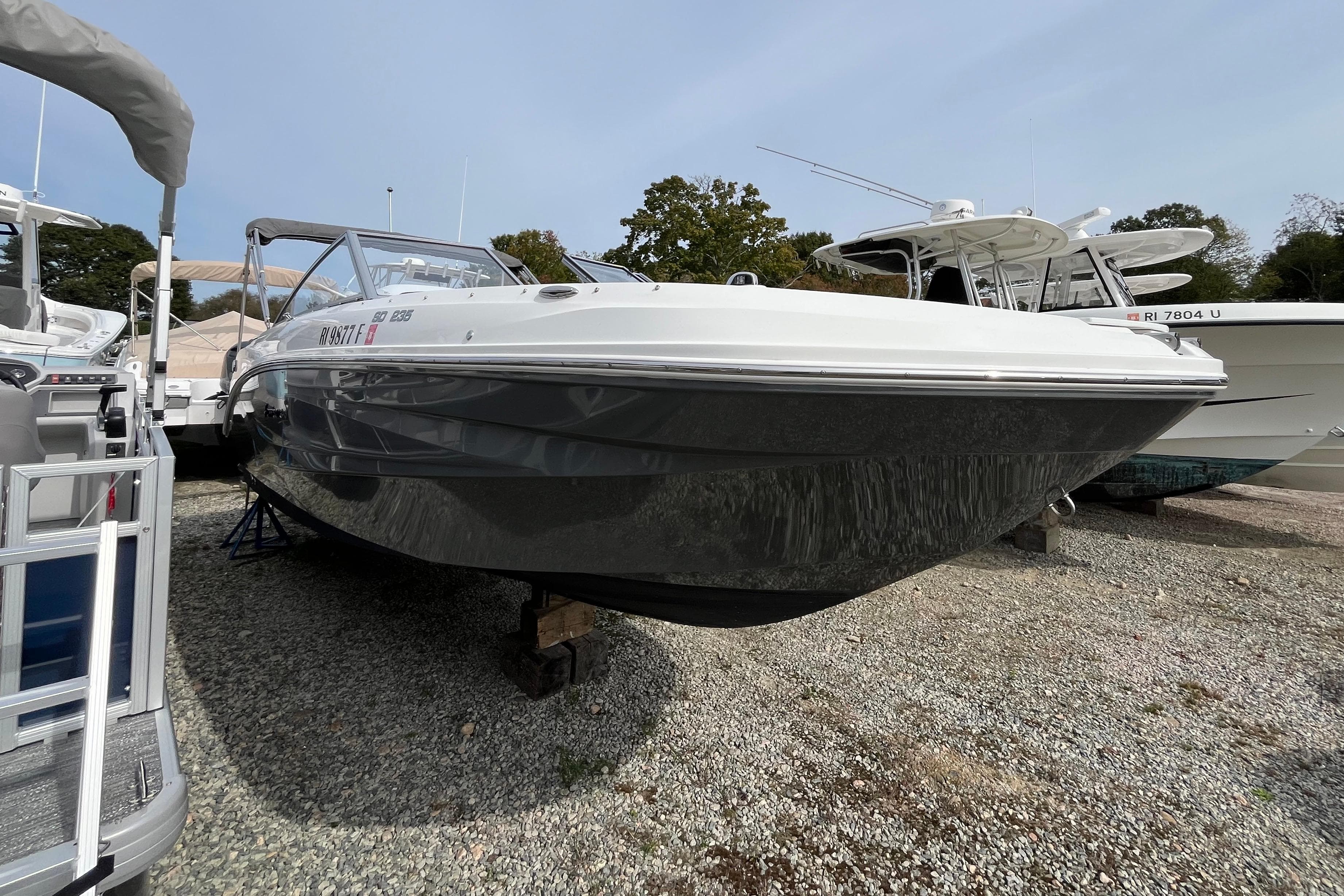2023 Hurricane SunDeck 235 OB boat displayed on gravel lot.