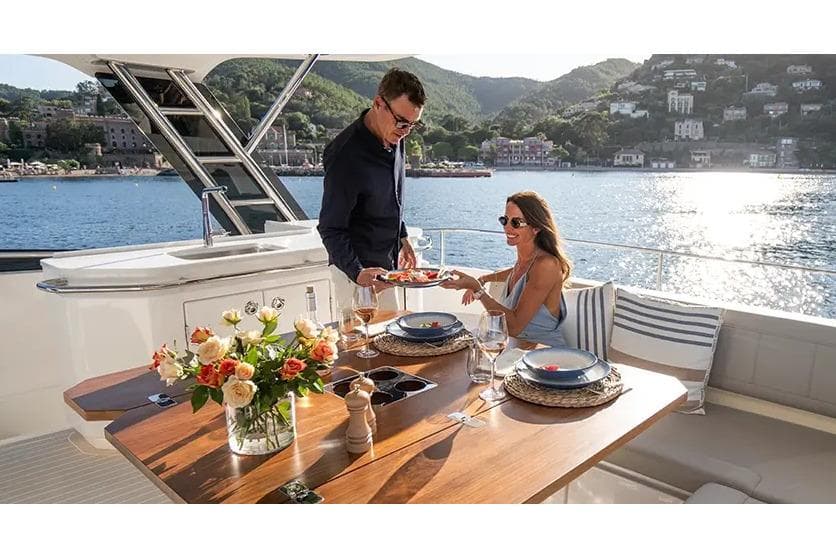 Manufacturer Provided Image: Couple dining on Aquila 46 Yacht, 2025 model, with scenic waterfront view.