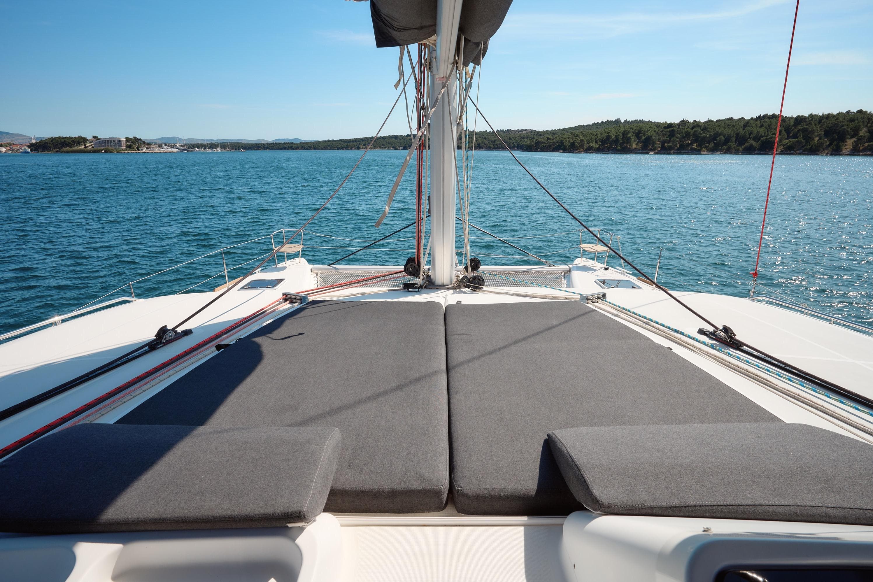 2018 Lagoon 450 catamaran deck with sunbeds, sailing on calm blue waters.