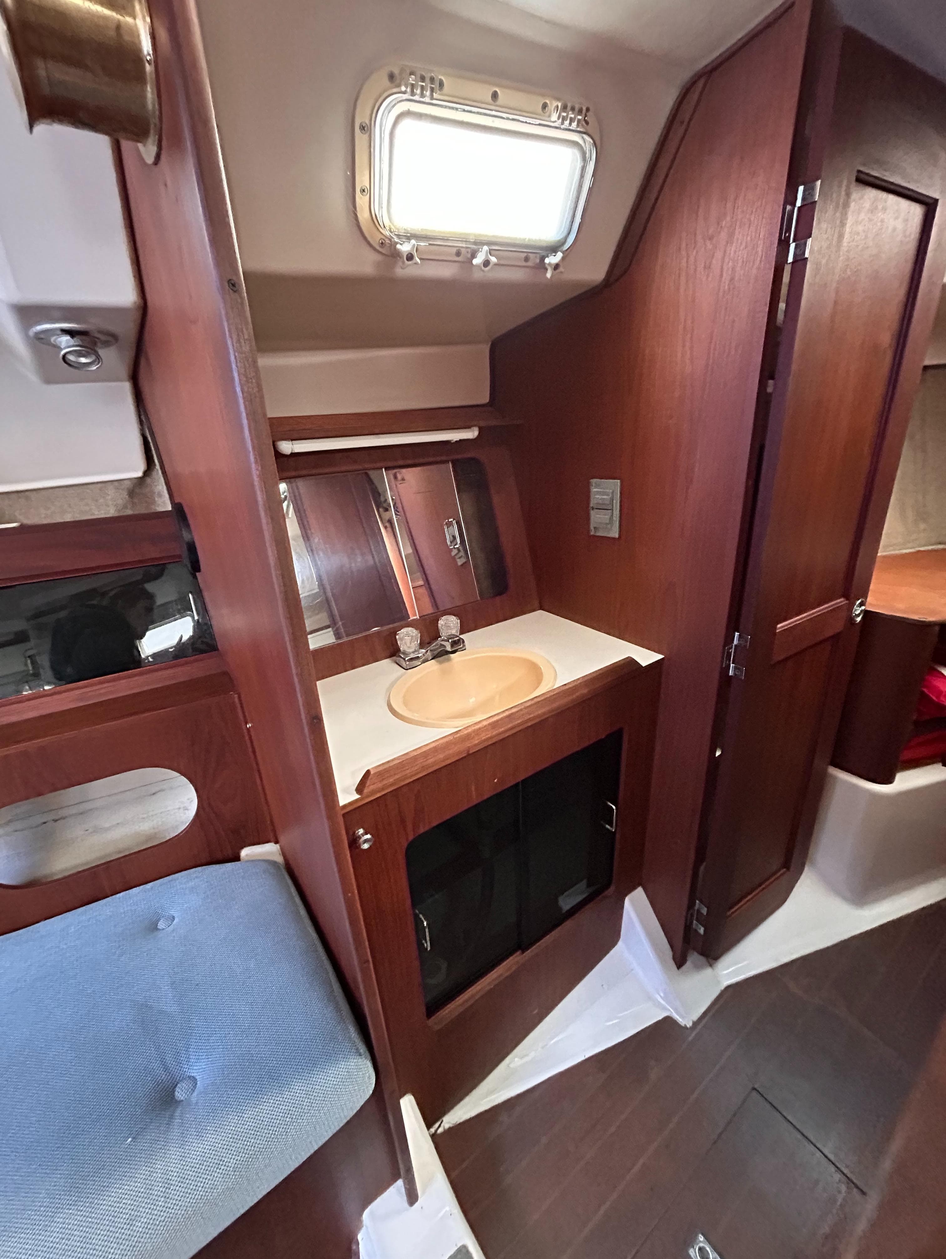 Interior of 1983 Hunter 34 sailboat with wooden cabinetry and compact sink area.