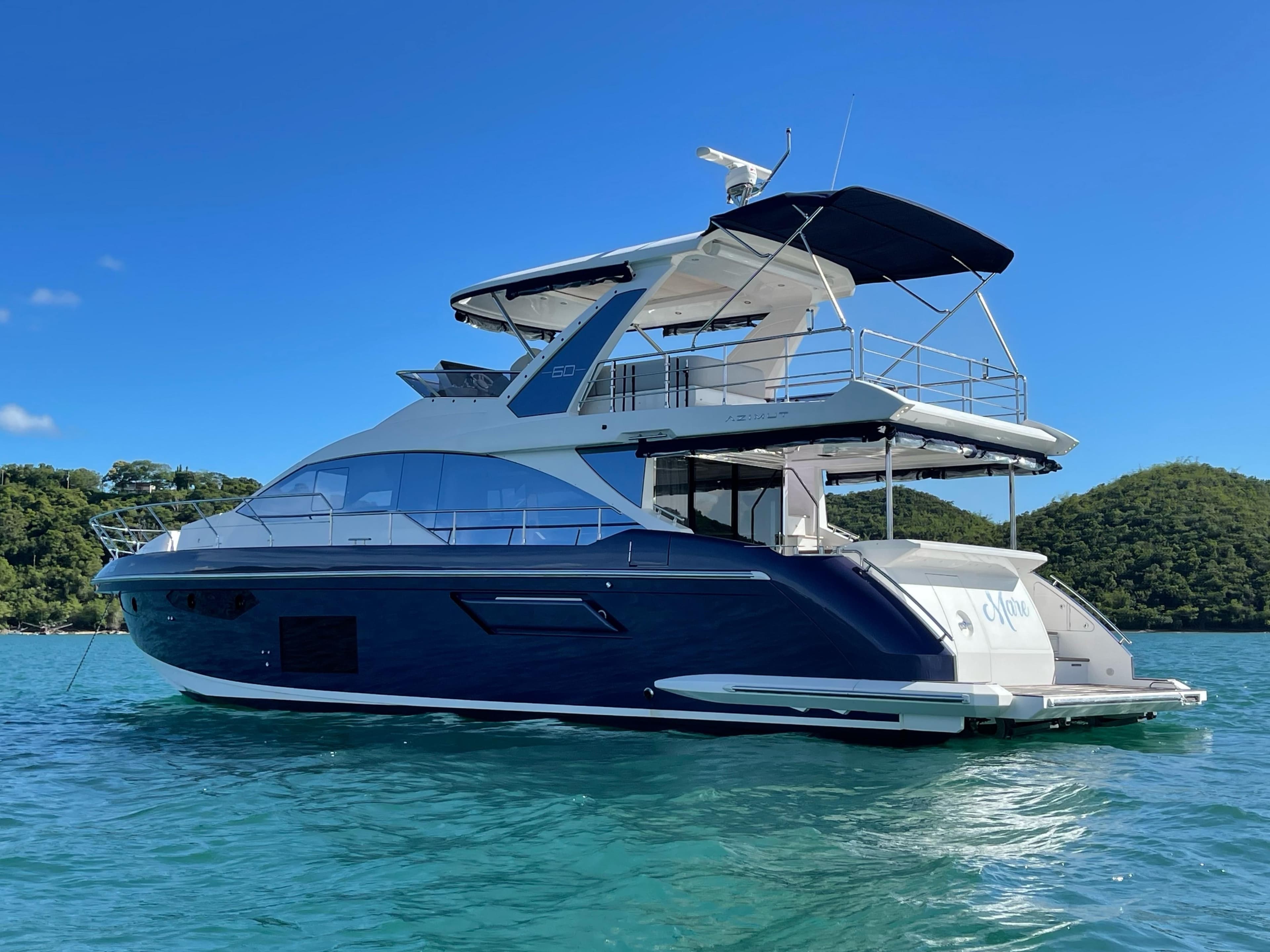 2020 Azimut 60 yacht on clear blue water with lush green hills in the background.