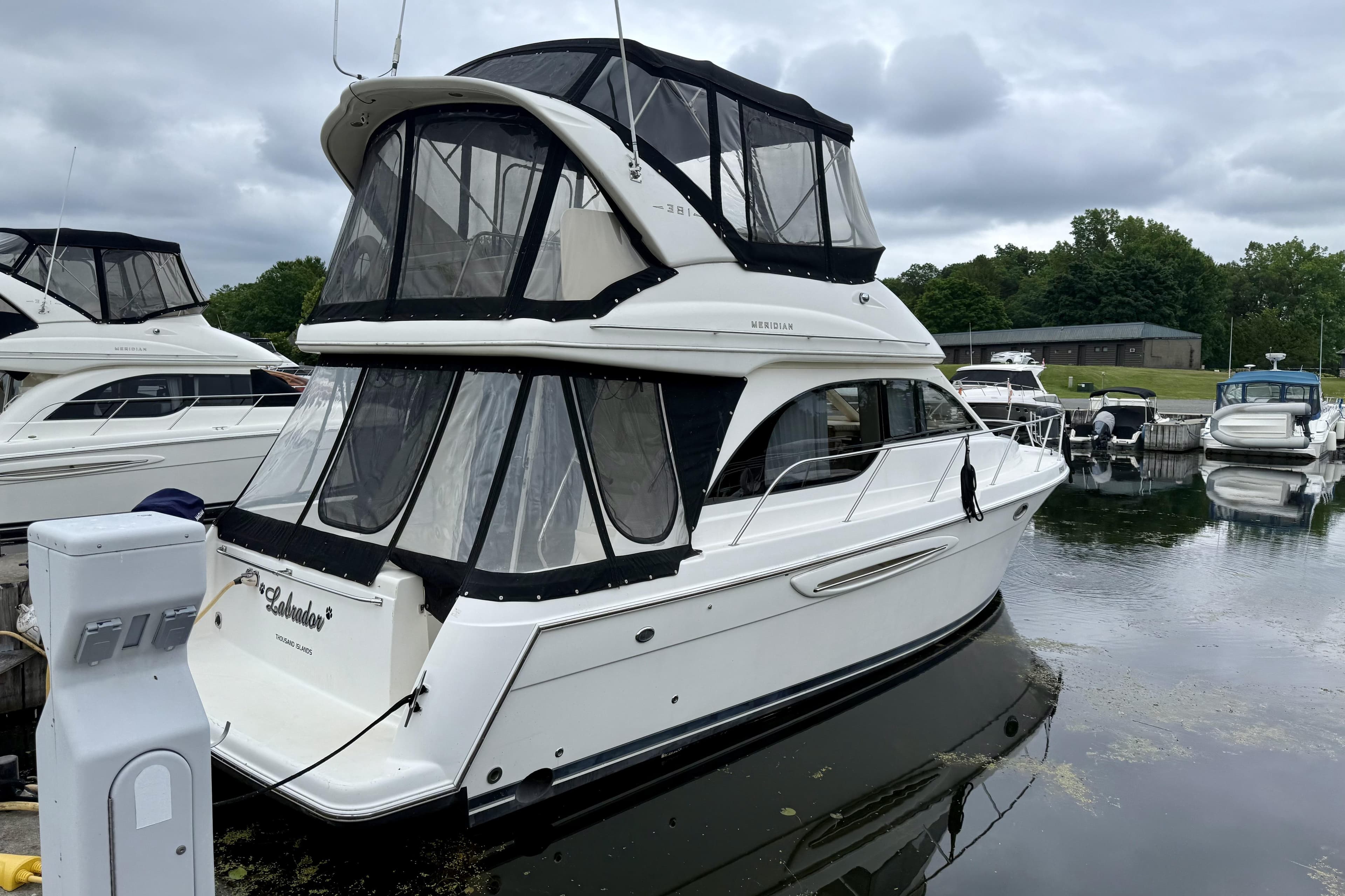 2004 Meridian 381 Sedan yacht docked at marina, featuring enclosed flybridge and sleek design.