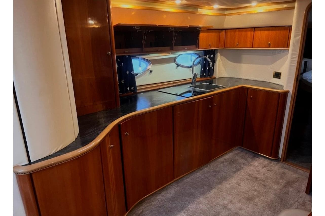 Luxurious wooden interior of a 1998 Princess V55 yacht kitchen with modern amenities.
