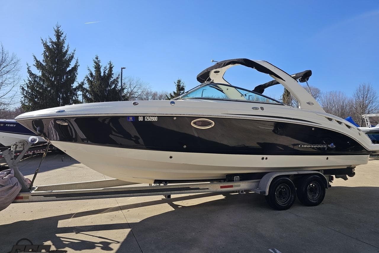 2010 Chaparral 276 SSX boat on trailer, parked outdoors under clear blue sky.