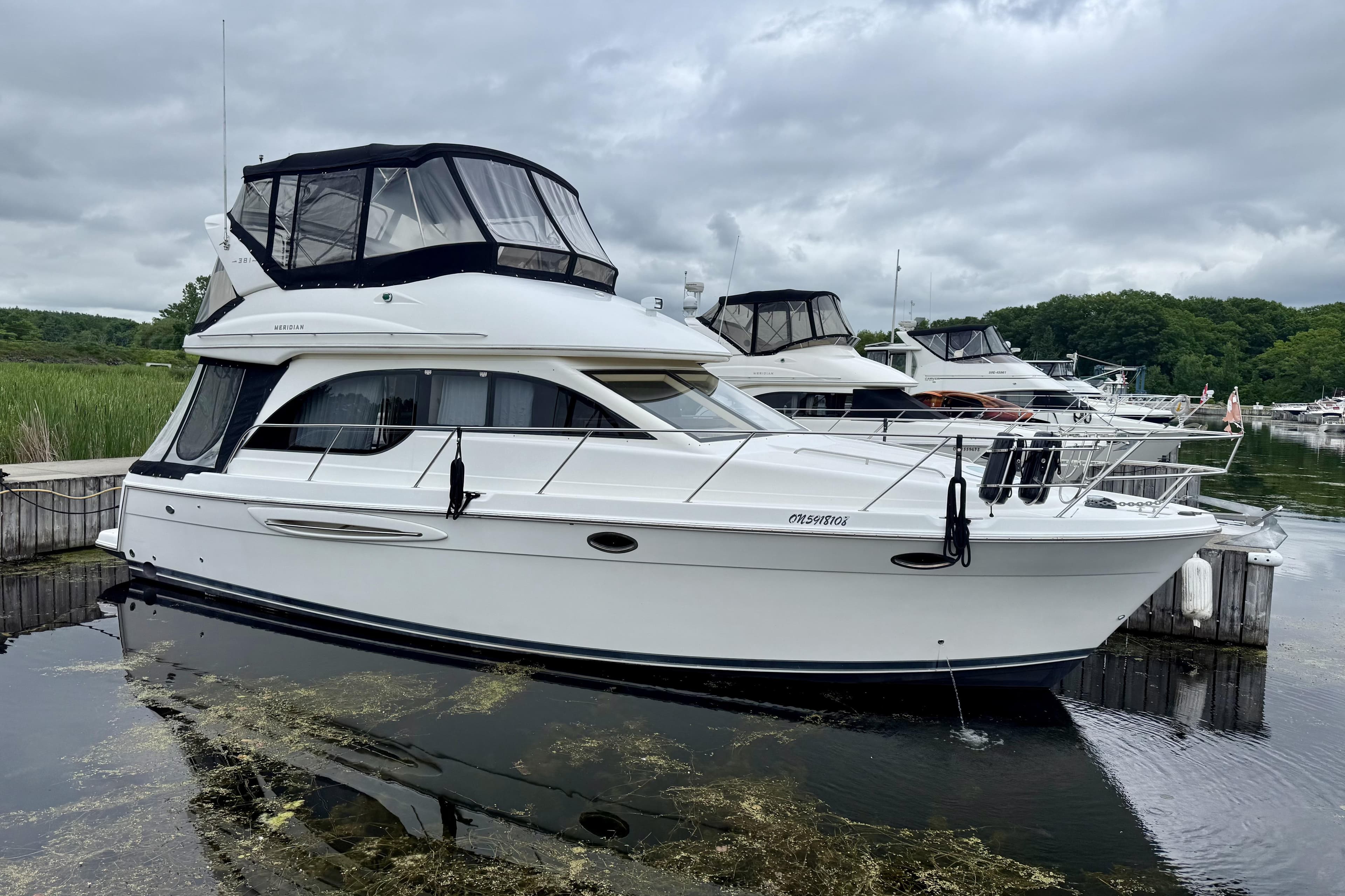 2004 Meridian 381 Sedan yacht docked in a marina under cloudy skies.