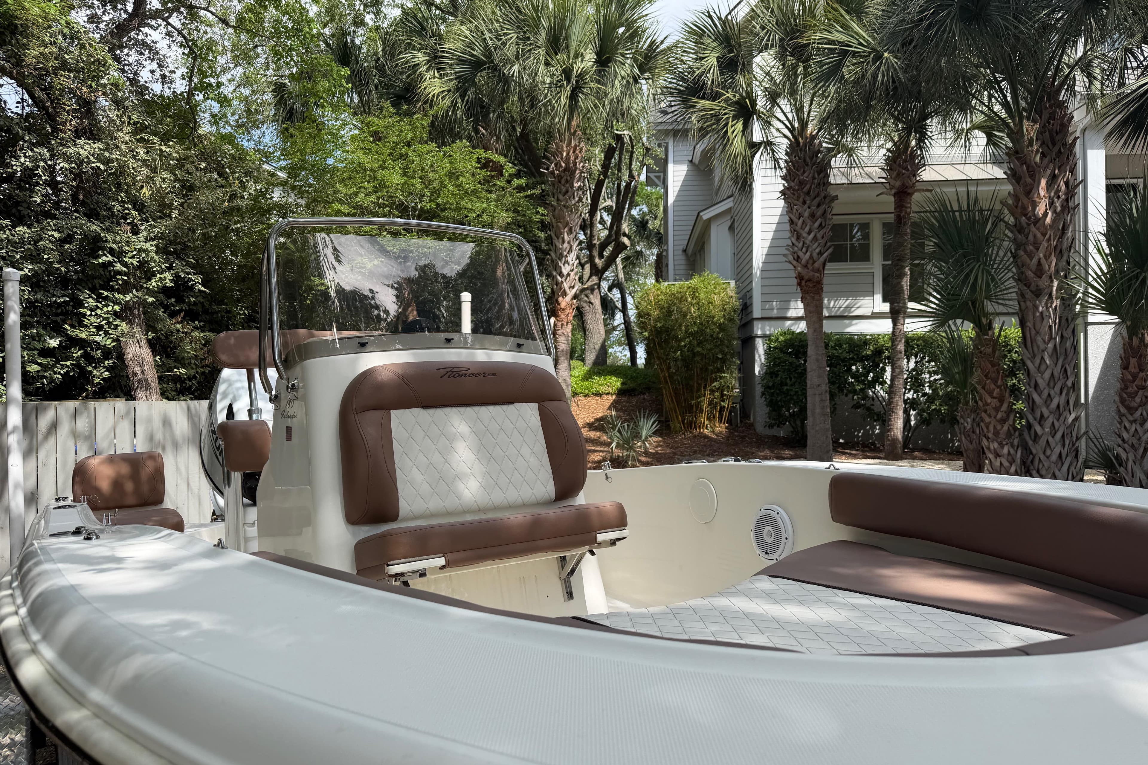 2023 Pioneer 180 Islander boat with brown seating, surrounded by palm trees.