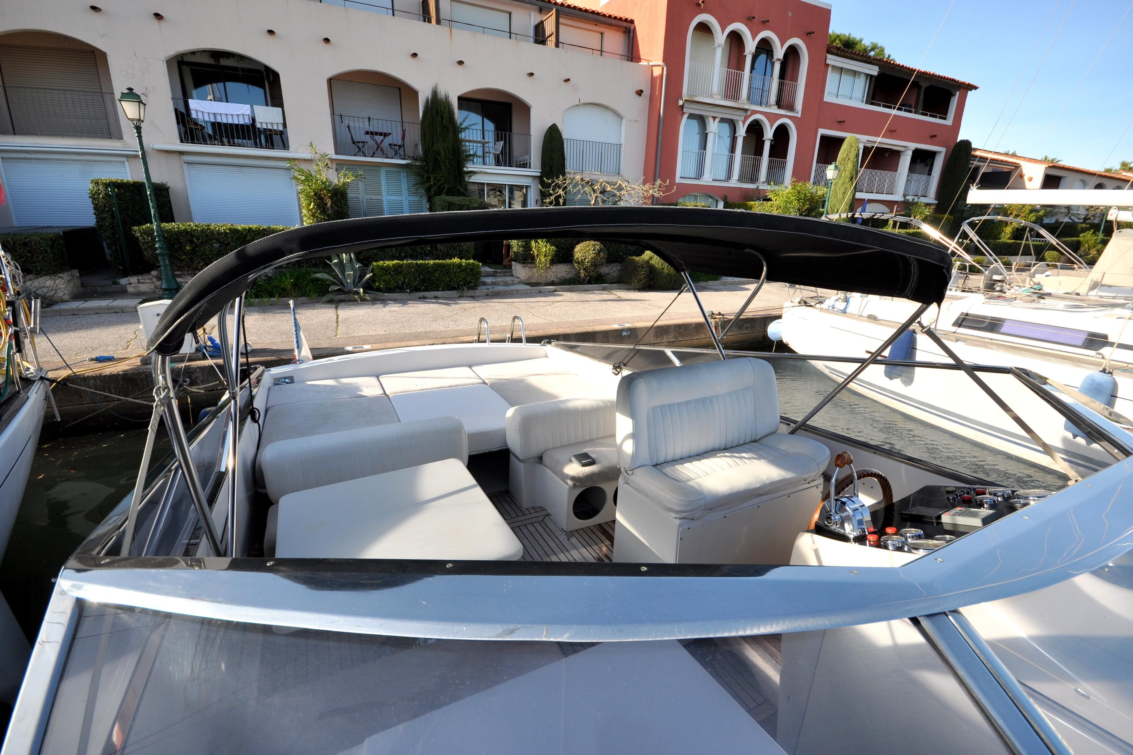 1996 Itama 38 yacht with spacious seating, docked near waterfront buildings.