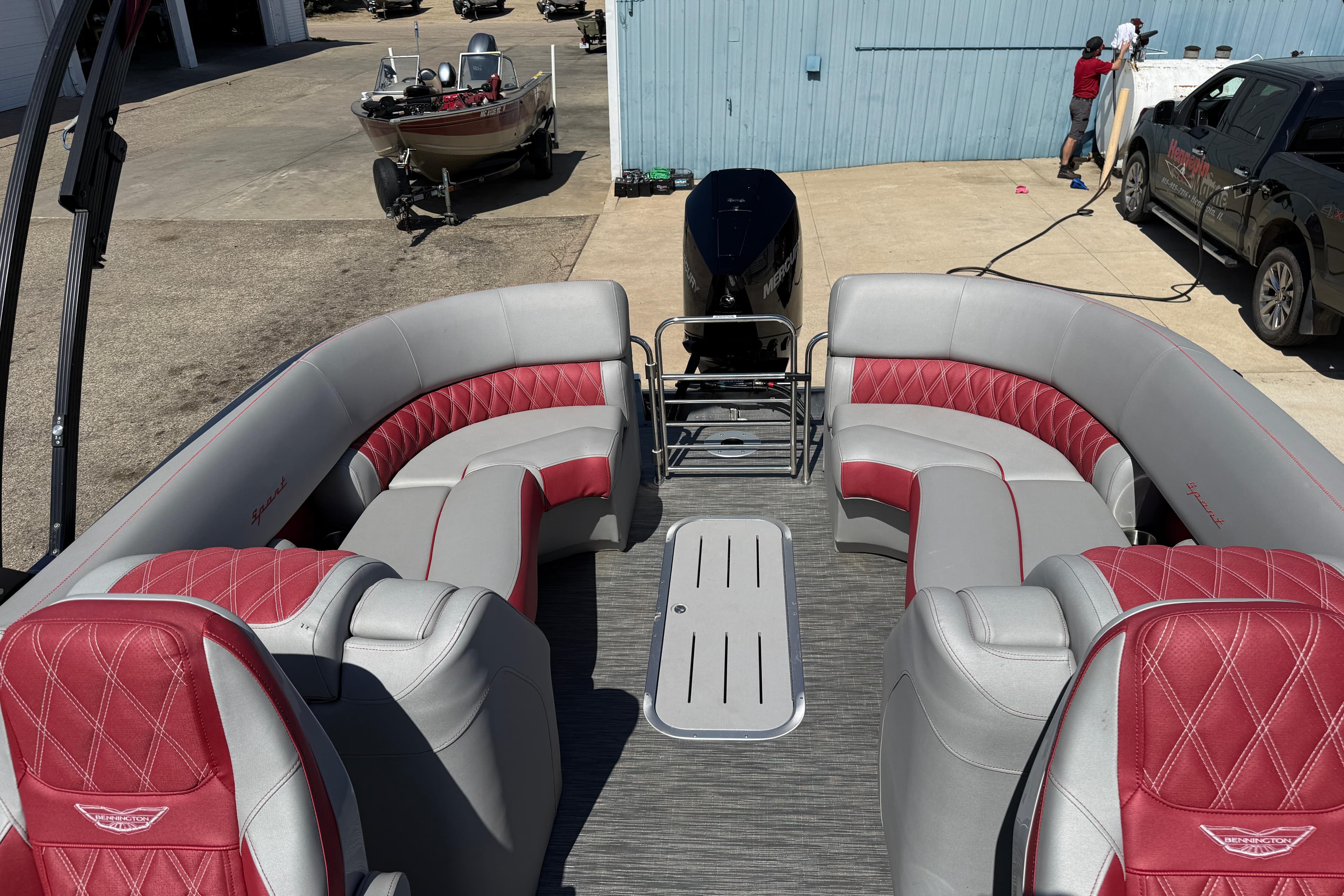 2022 Bennington R 24 Quad Bench Bowrider with red and gray seating in a marina setting.