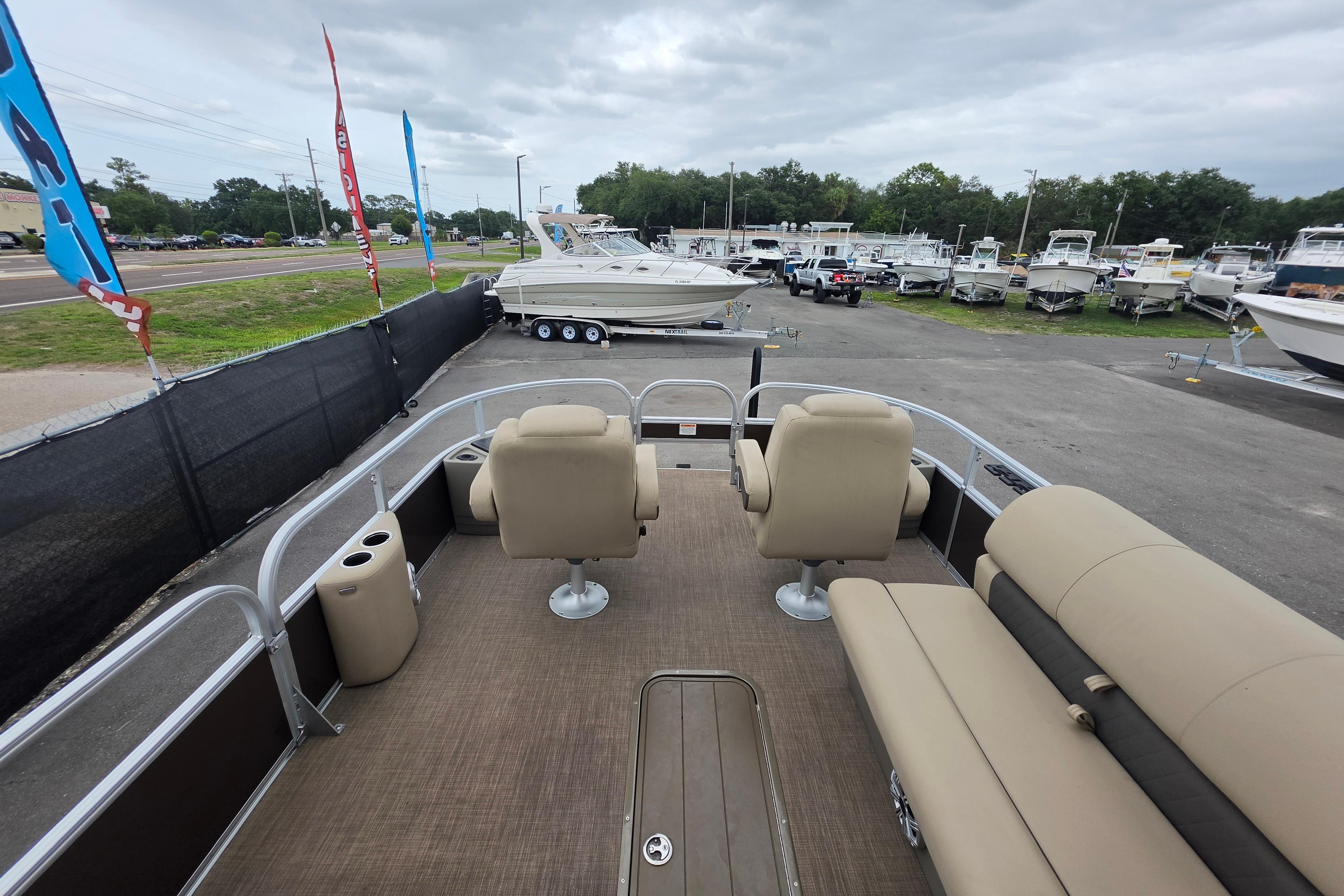 2023 Sun Tracker Bass Buggy 18 DLX pontoon boat at a dealership, showcasing seating and deck layout.