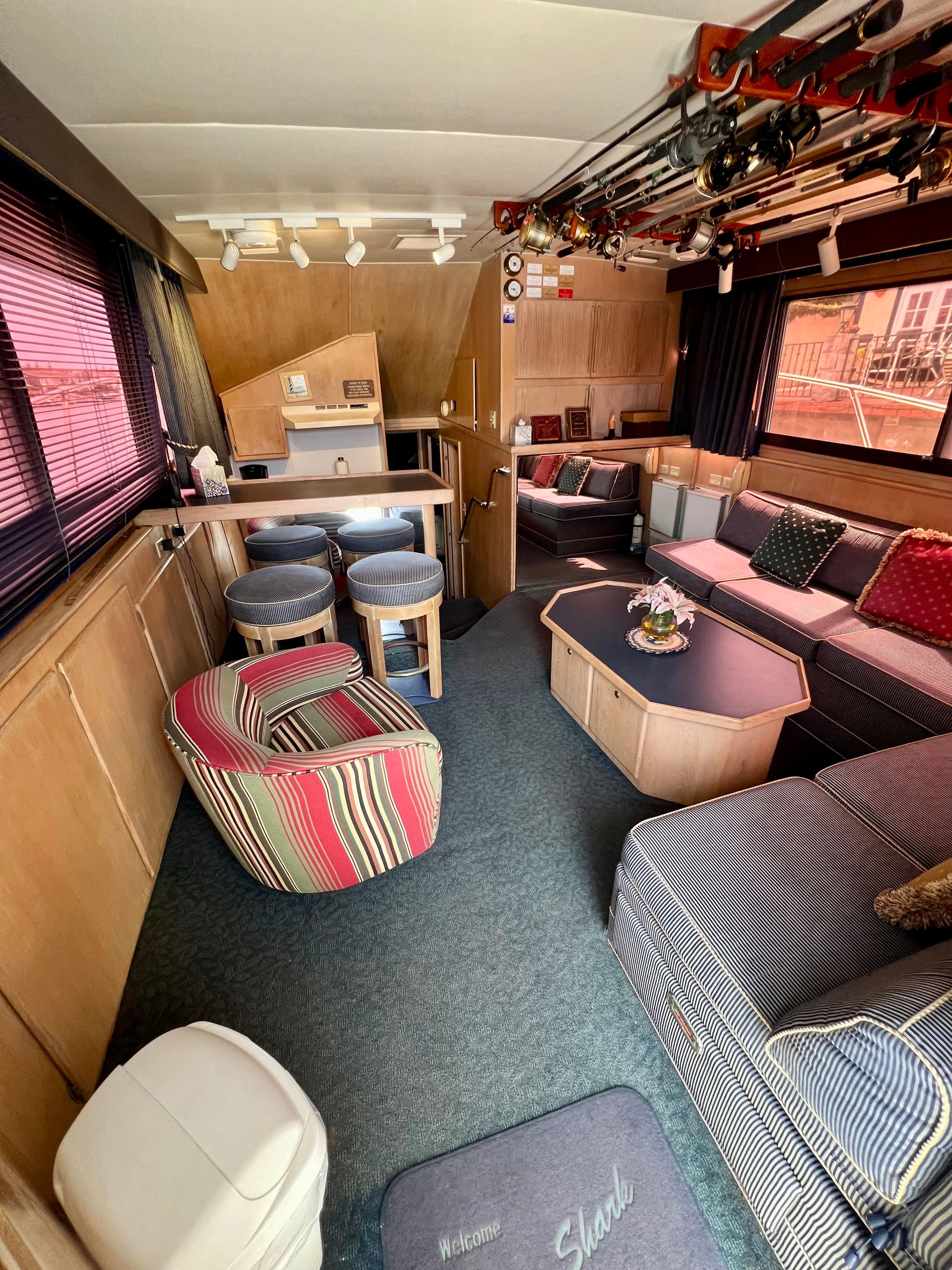 Interior of 1988 Hatteras 48 Convertible yacht with cozy seating and fishing rods.