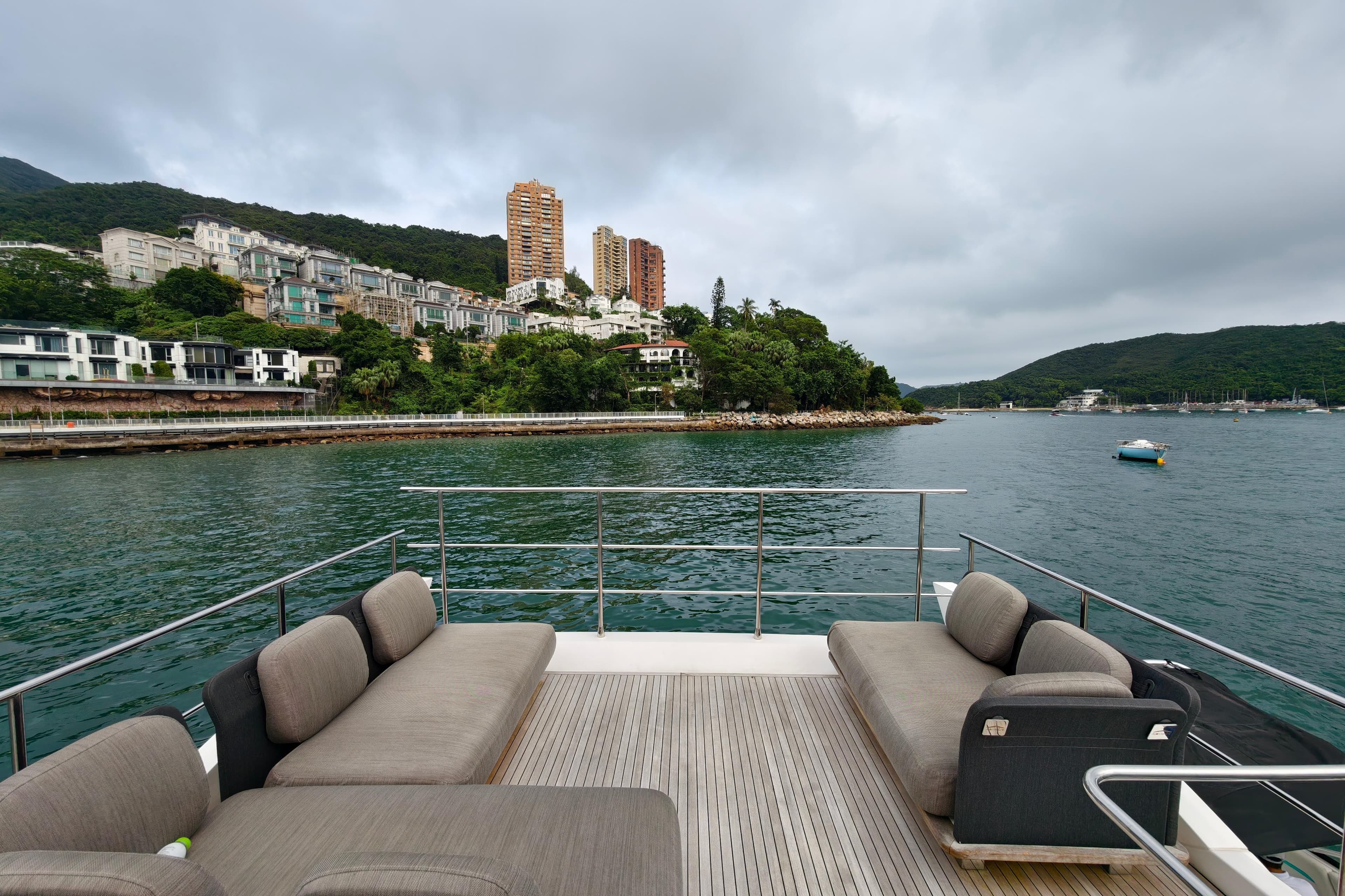 Luxurious 2017 Azimut 66 yacht deck with scenic coastal view and modern architecture.