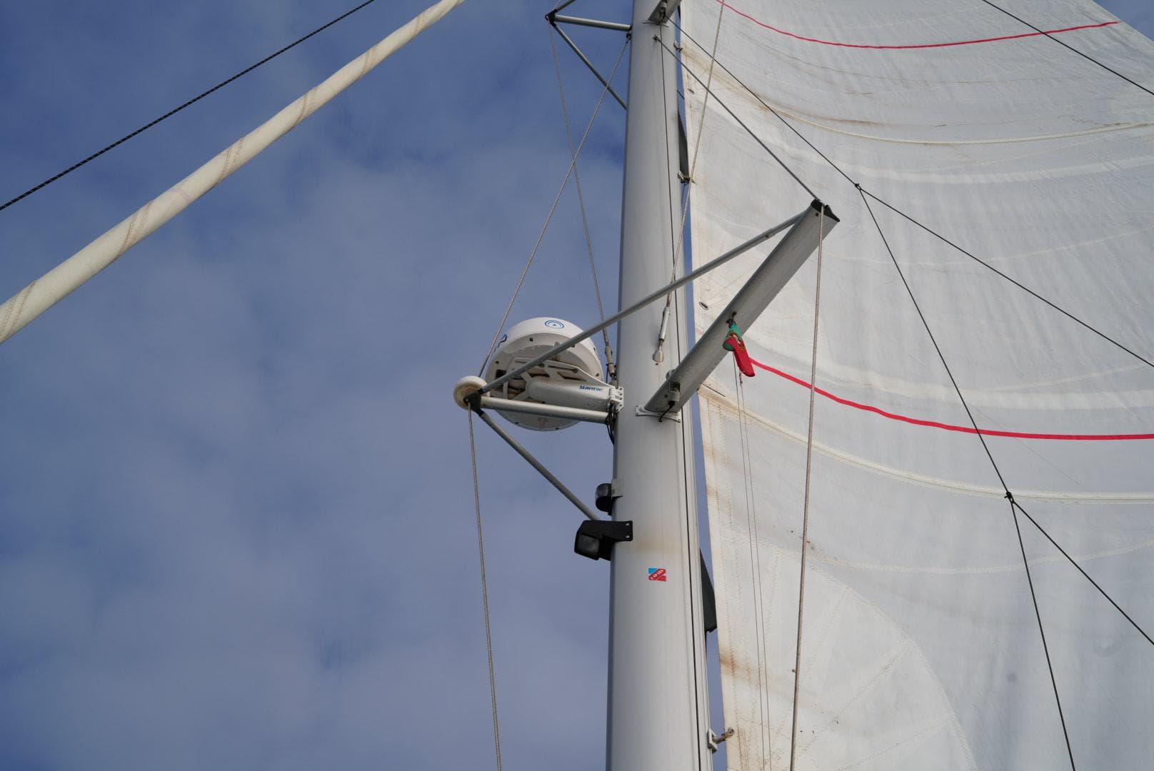 Sail and mast of 2022 Fountaine Pajot Elba Quatour against a cloudy sky.