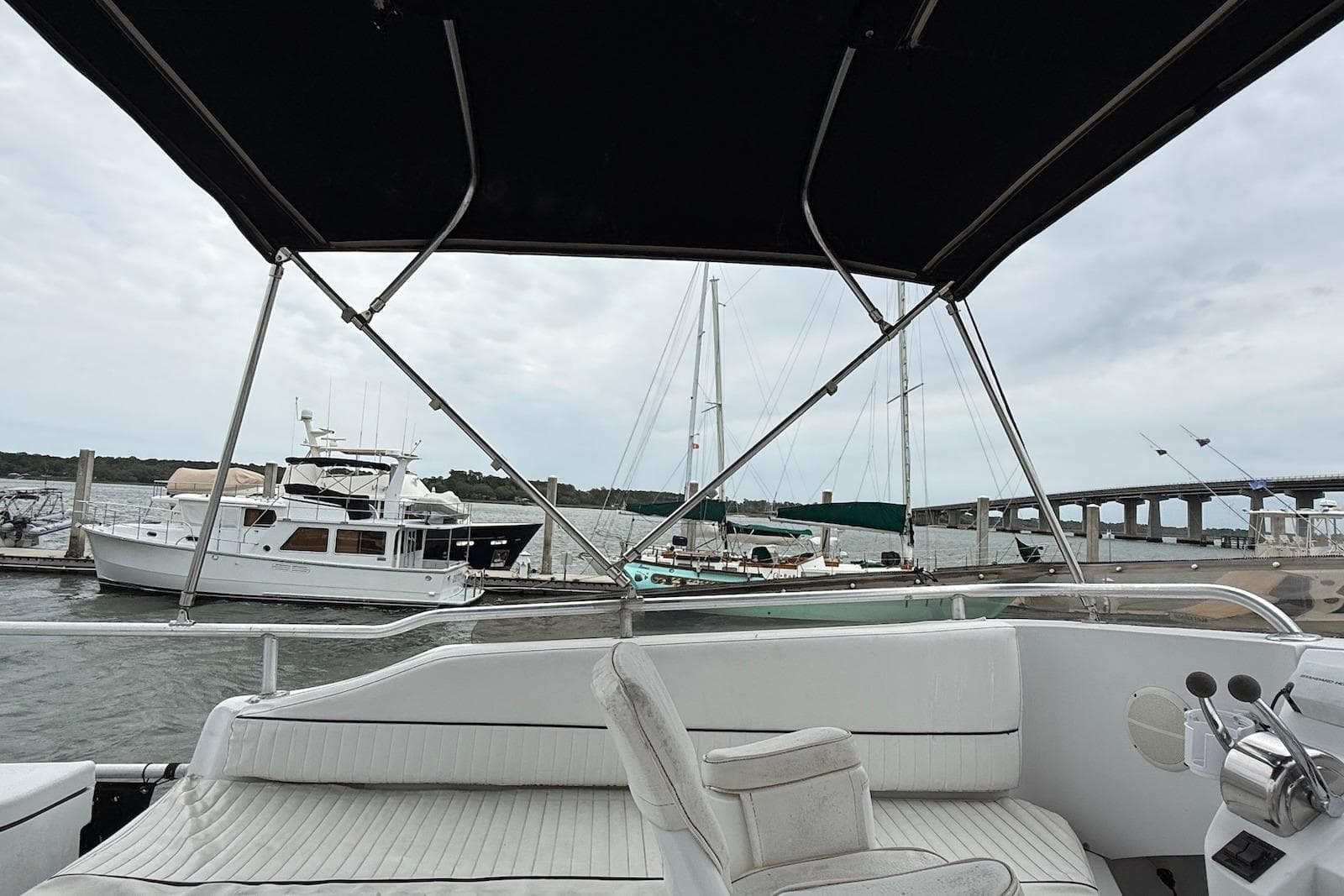 1998 Mainship 350 Trawler interior view at marina, with boats and bridge in background.