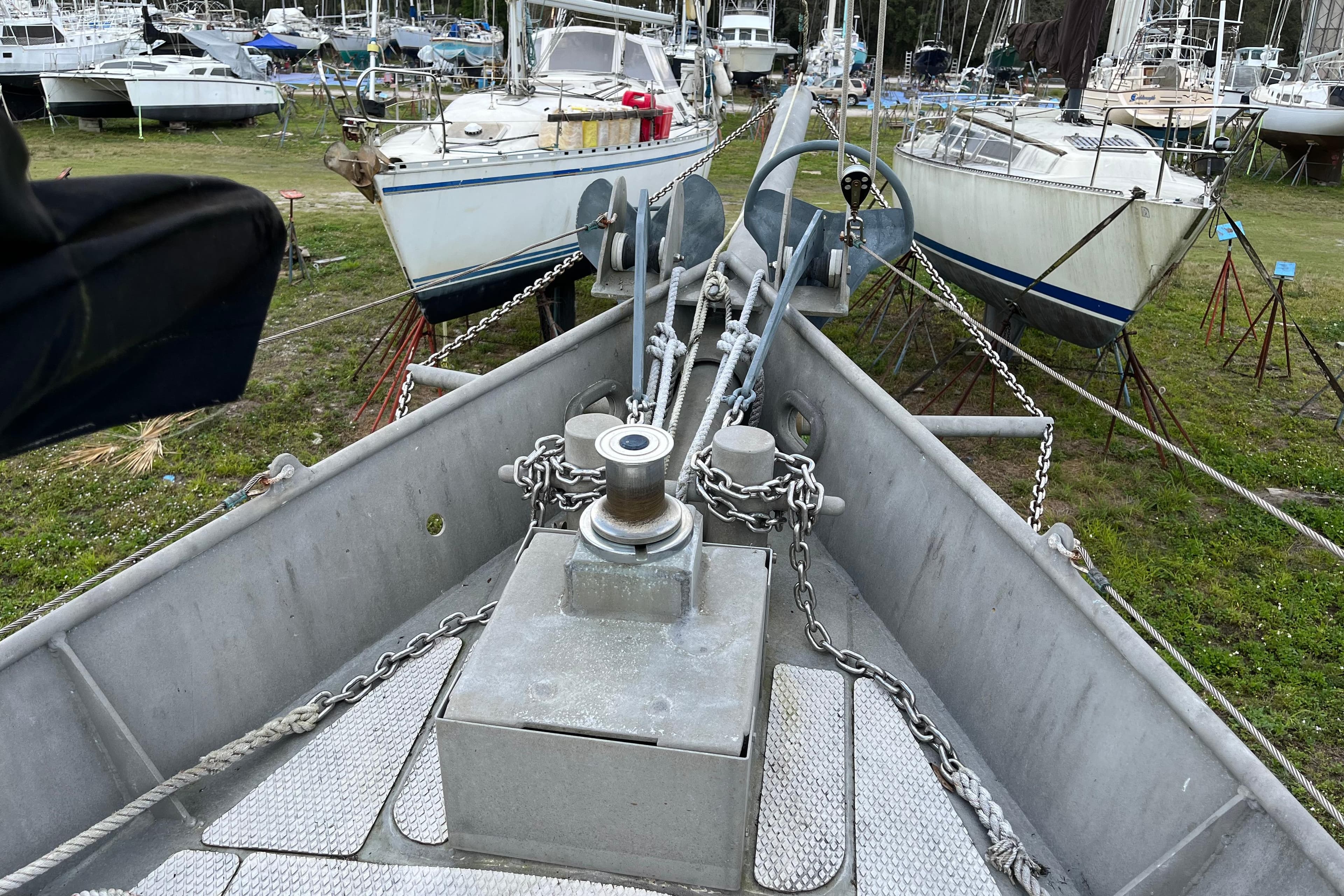 Bow of 1974 Colvin Gazelle Custom sailboat in a boatyard, surrounded by other vessels.