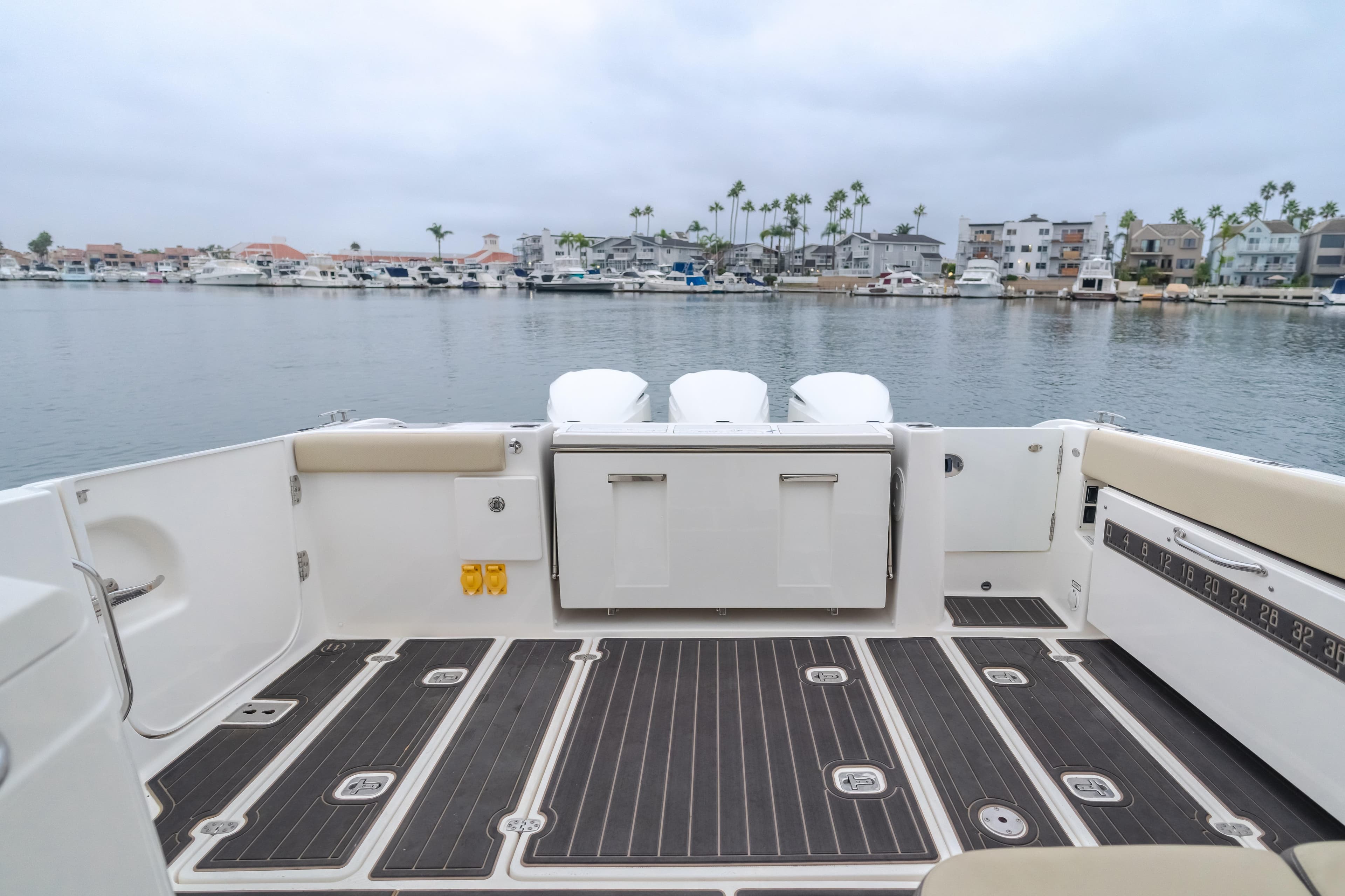 2018 Pursuit boat deck with seating, overlooking a marina with palm trees and boats.