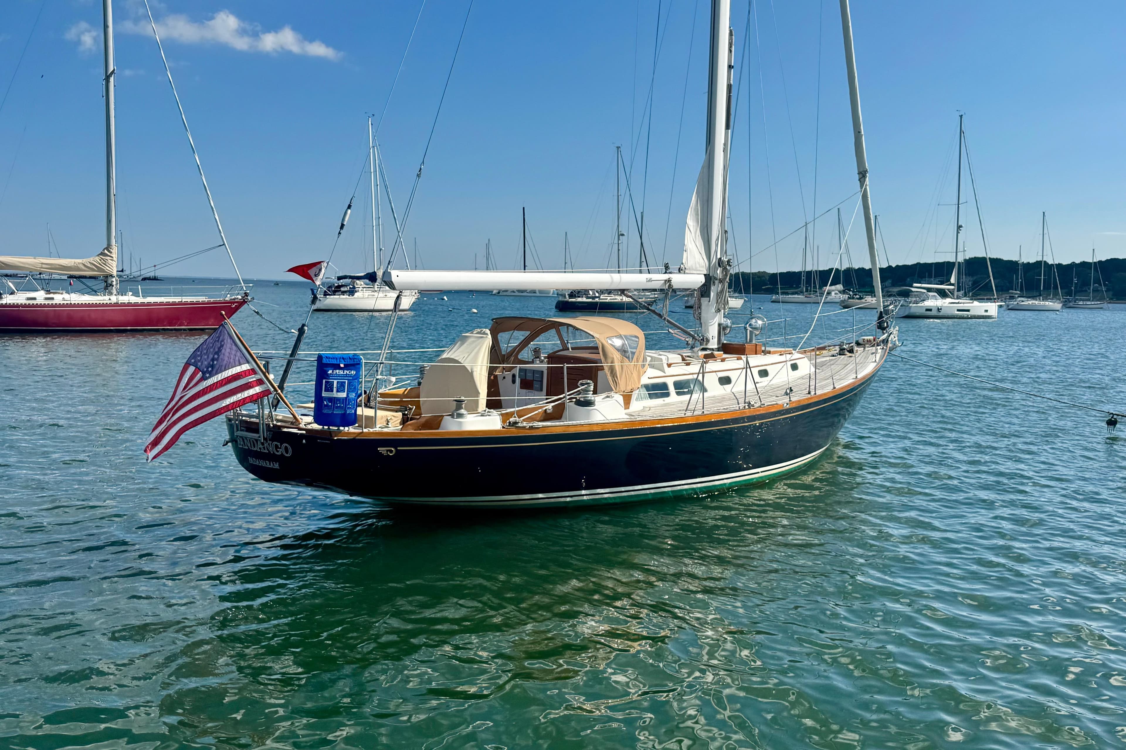 1982 Hinckley Bermuda 40 MK III sailboat on calm water, displaying an American flag.