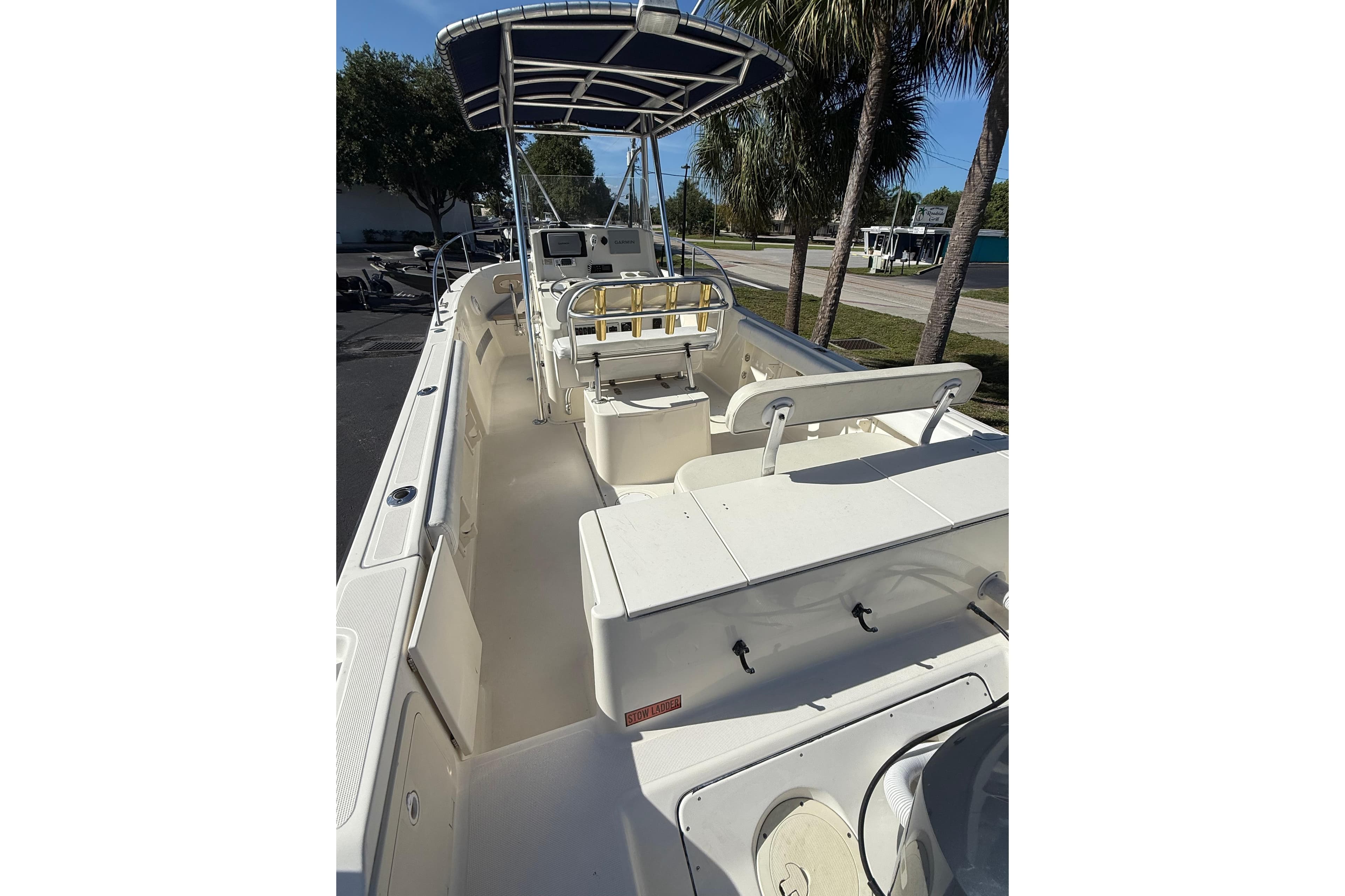 2000 Pursuit 2470 Center Console boat with spacious deck and canopy, parked outdoors.