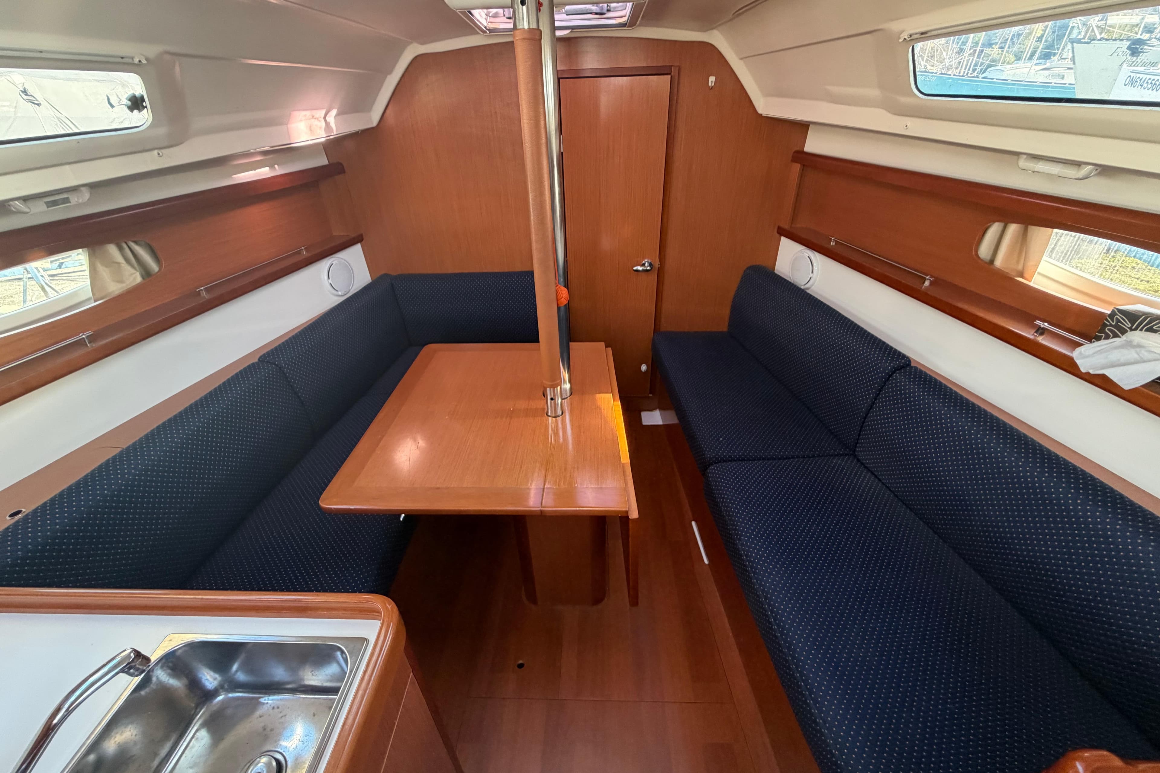 Interior of 2008 Beneteau 31 sailboat with wooden table and blue seating.