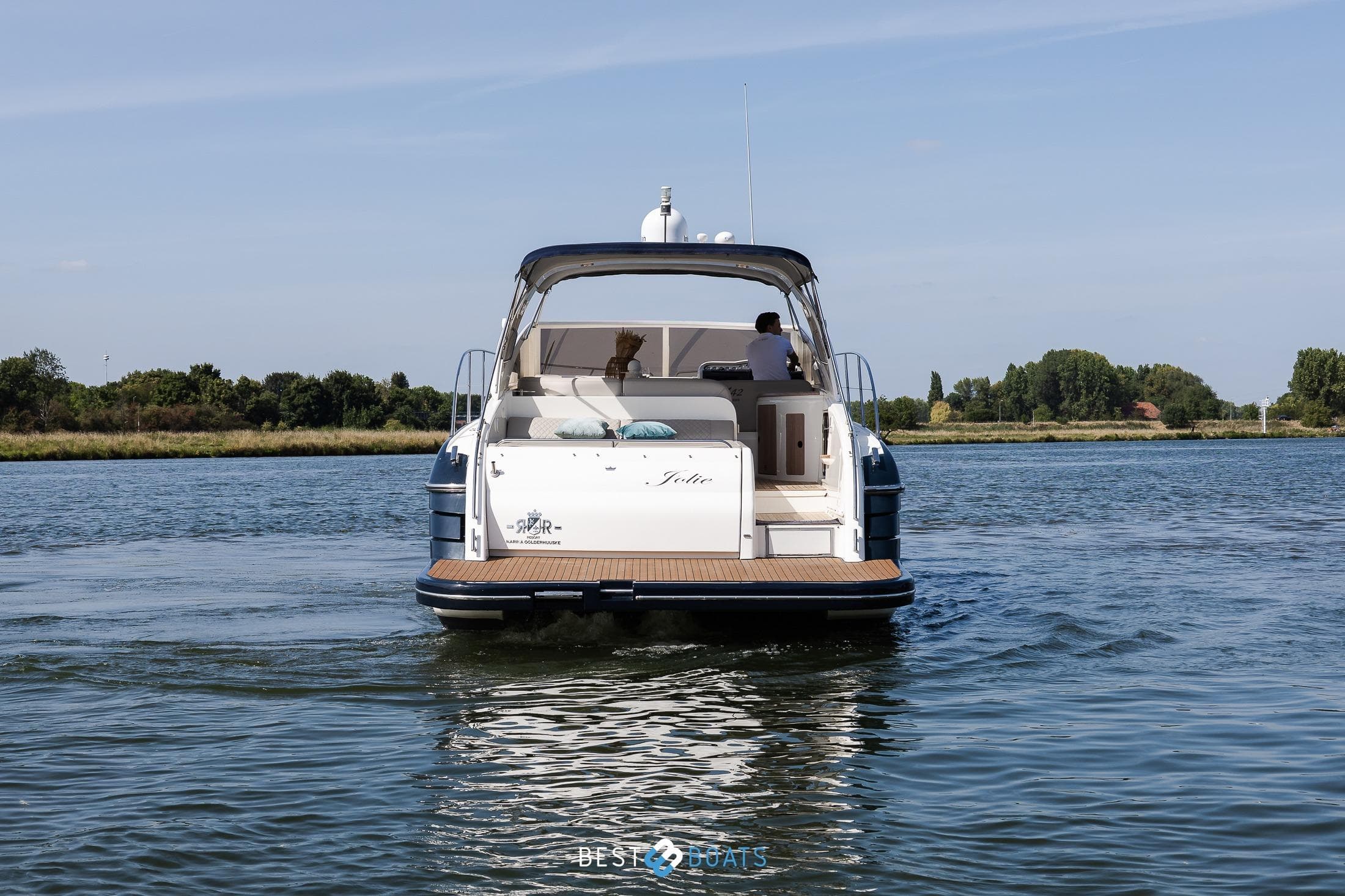 2006 Princess V42 yacht cruising on a serene river with lush greenery.