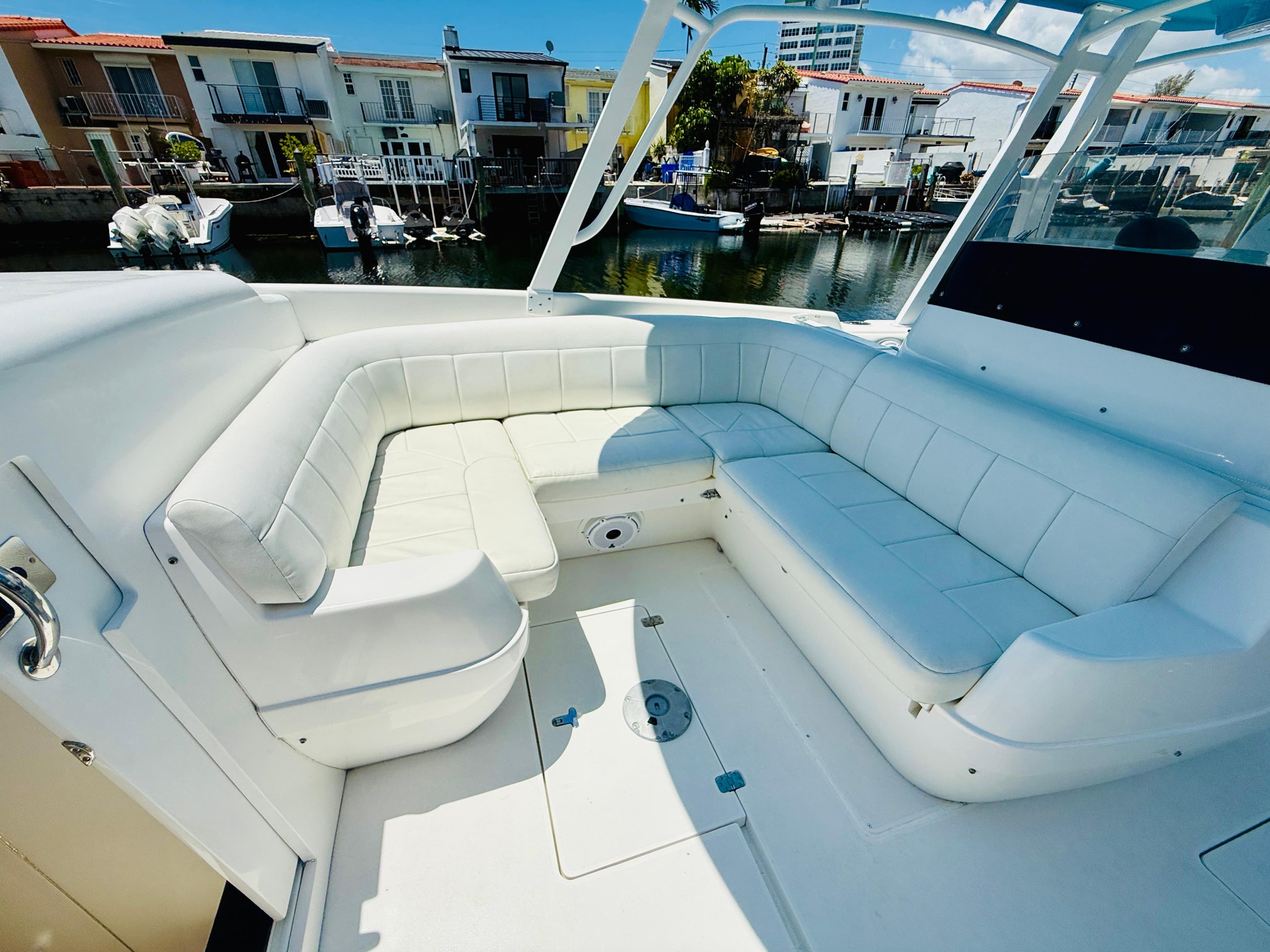 2003 Intrepid 377 boat with spacious white seating area, docked near waterfront homes.
