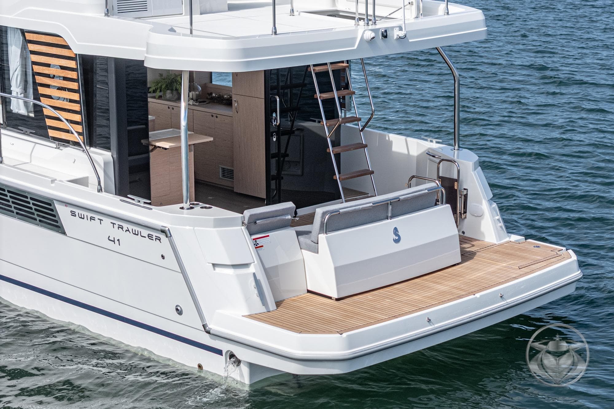 2026 Beneteau Swift Trawler 41 Fly, rear view on water, showcasing deck and ladder.