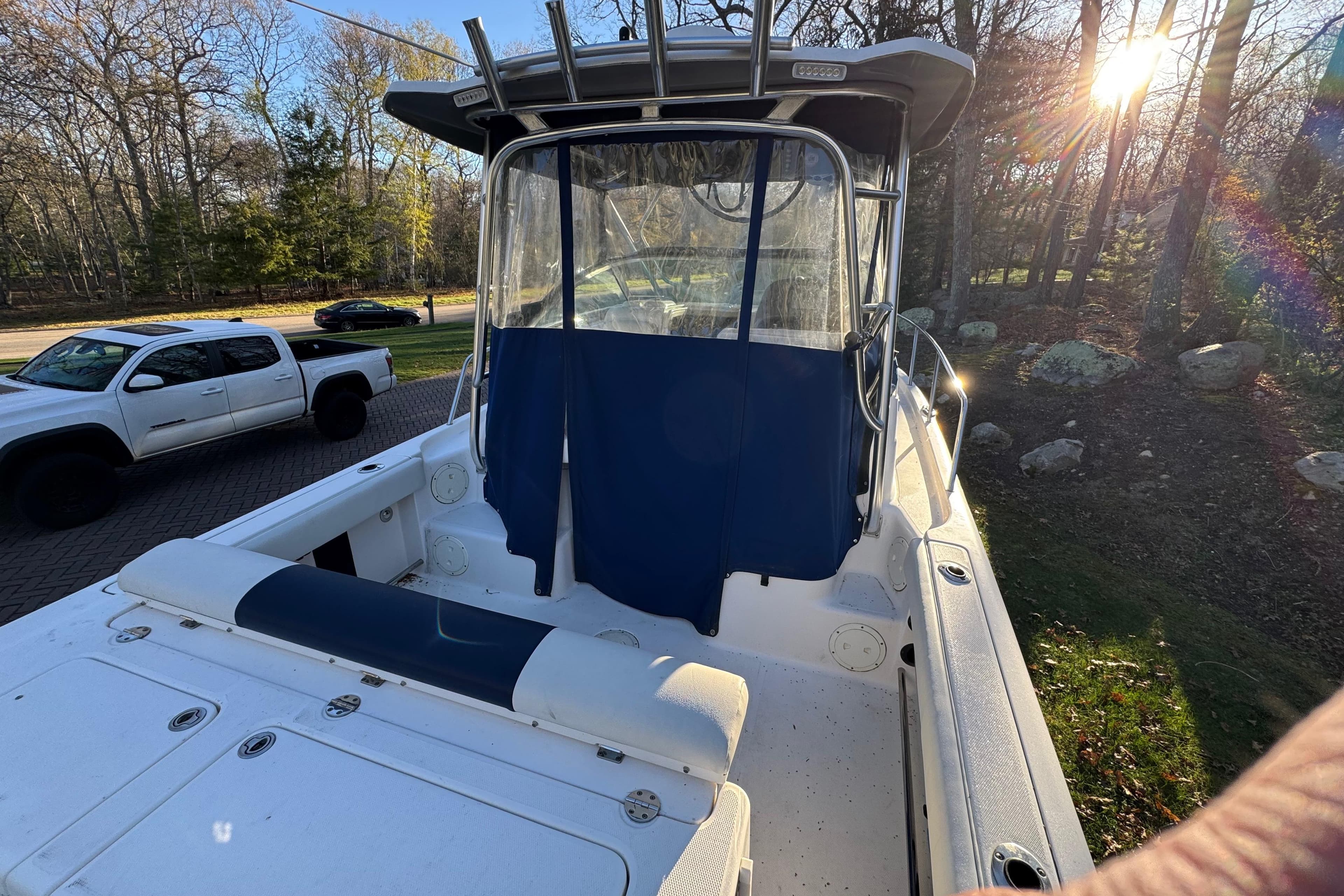 2014 Robalo R265 Walkaround boat with blue canopy, parked near a white truck.