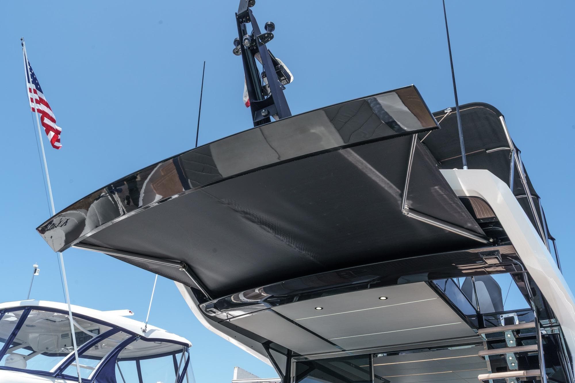 Sunseeker 65 Sport Yacht 2023, sleek design, rear view, with American flag in background.