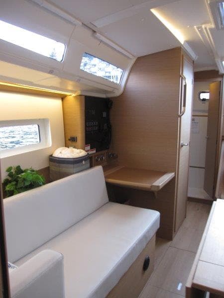 Interior of 2024 Jeanneau 380 sailboat with modern seating and wooden finishes.
