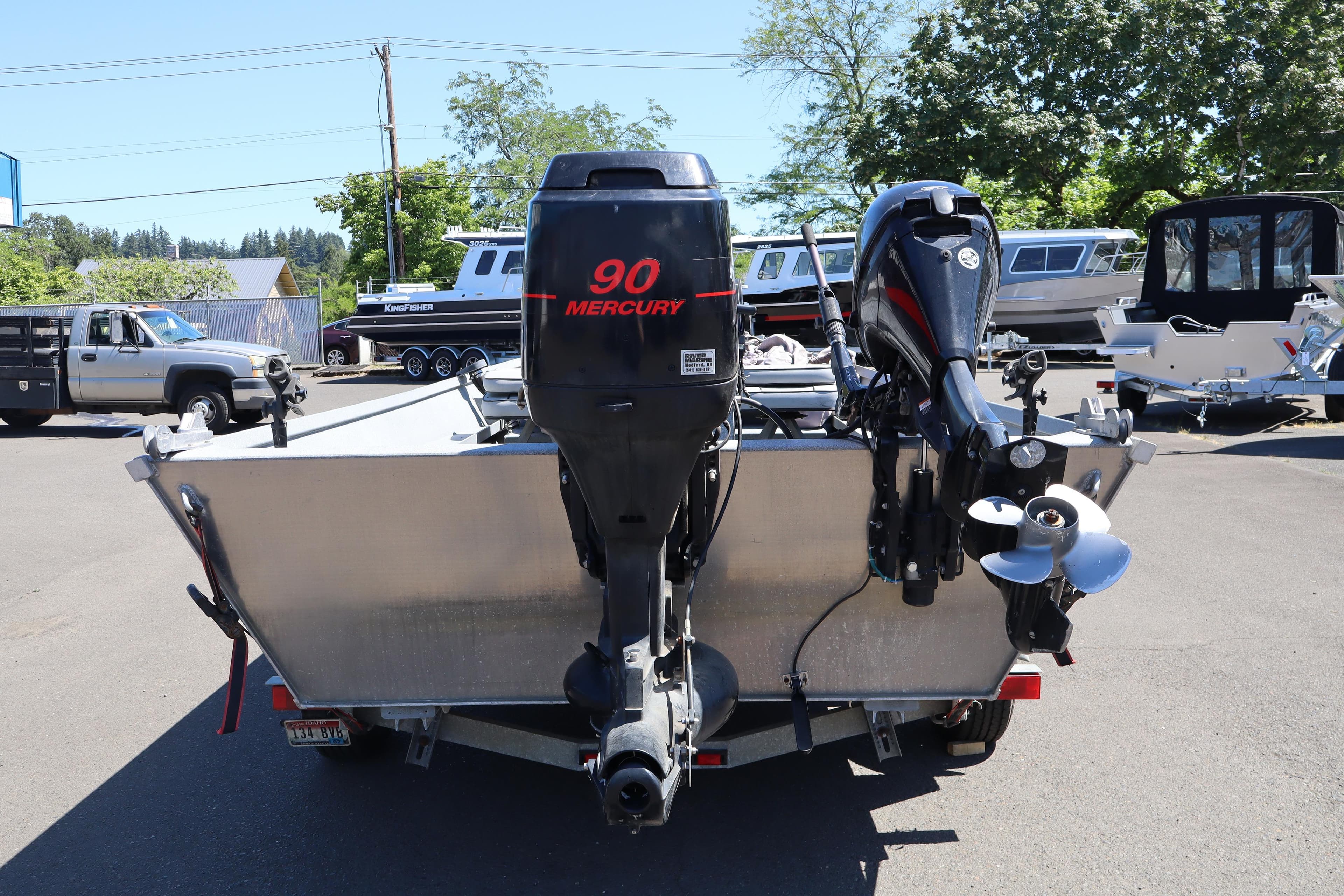 2003 Alumaweld Flatbottom boat with Mercury 90 engine, parked outdoors.