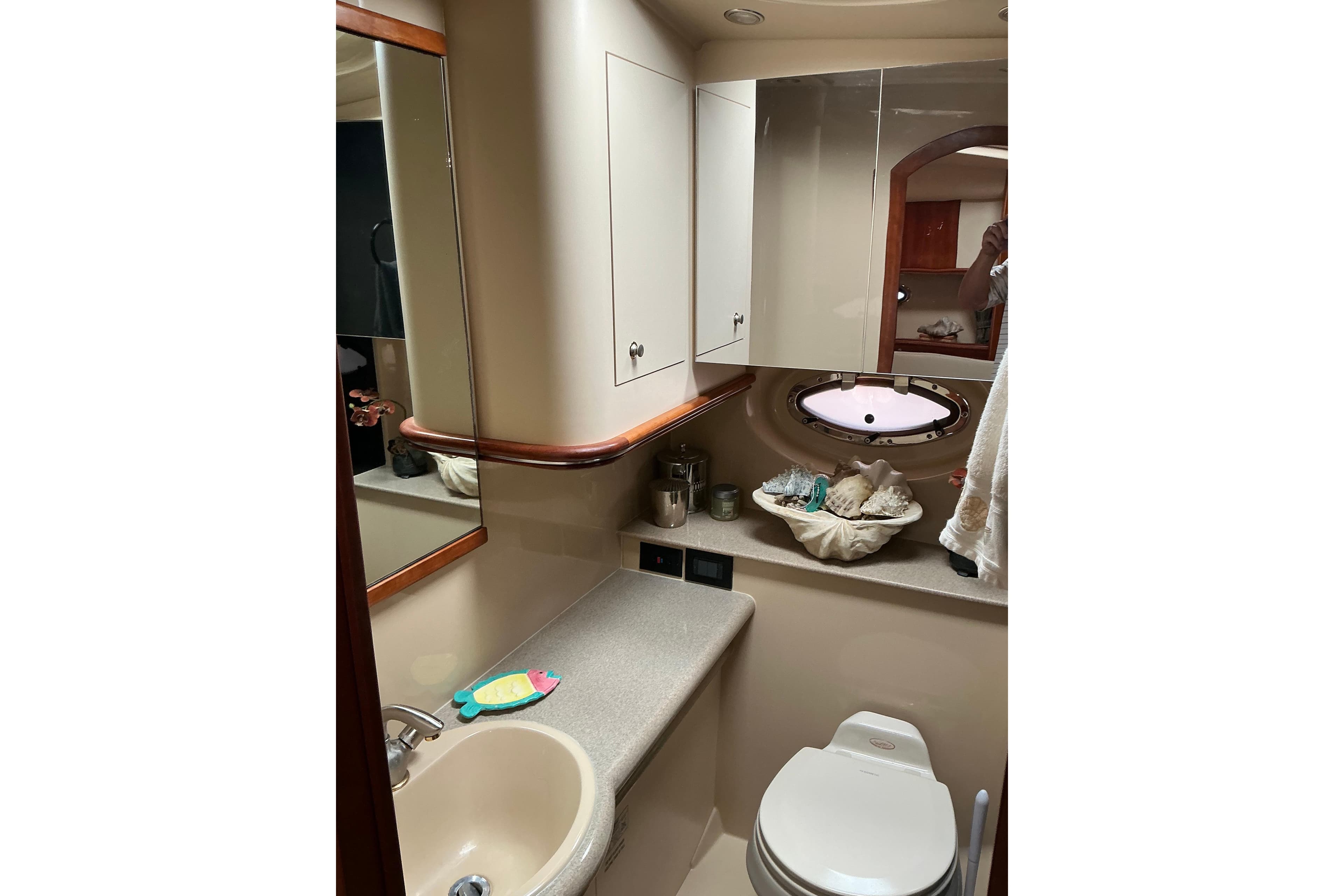 2005 Cruisers Yachts 370 Express bathroom with sink, mirror, and porthole window.