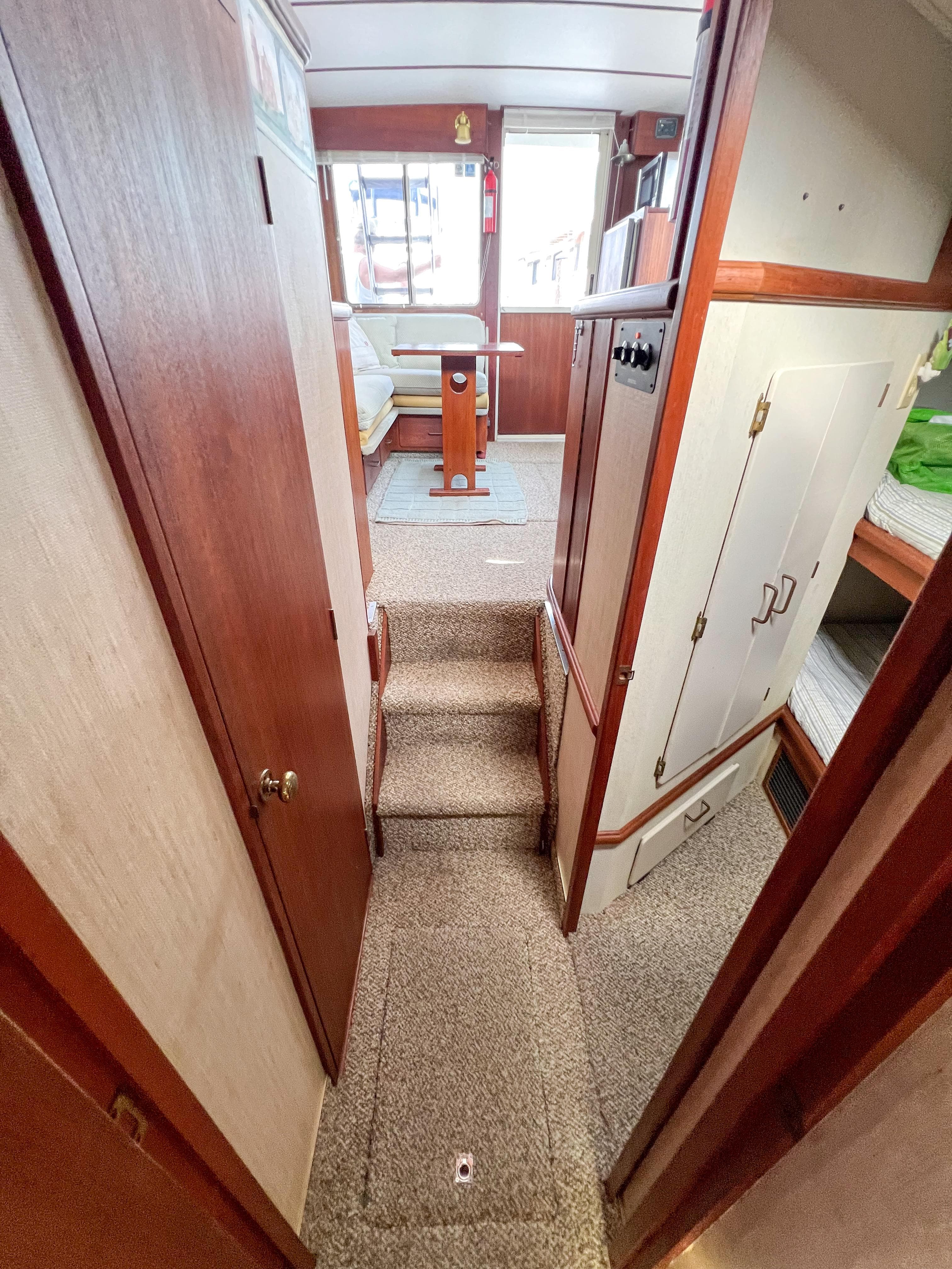 1987 Tollycraft 34 Sport Sedan interior hallway with carpeted steps and wooden cabinetry.