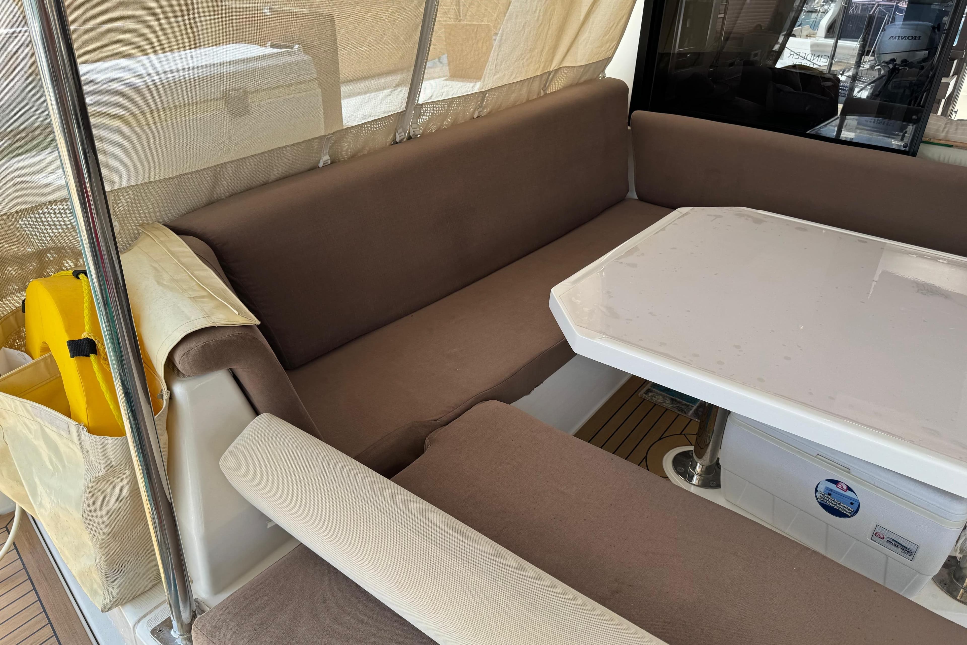 Interior seating area of a 2019 Leopard 45 yacht with brown cushions and a white table.