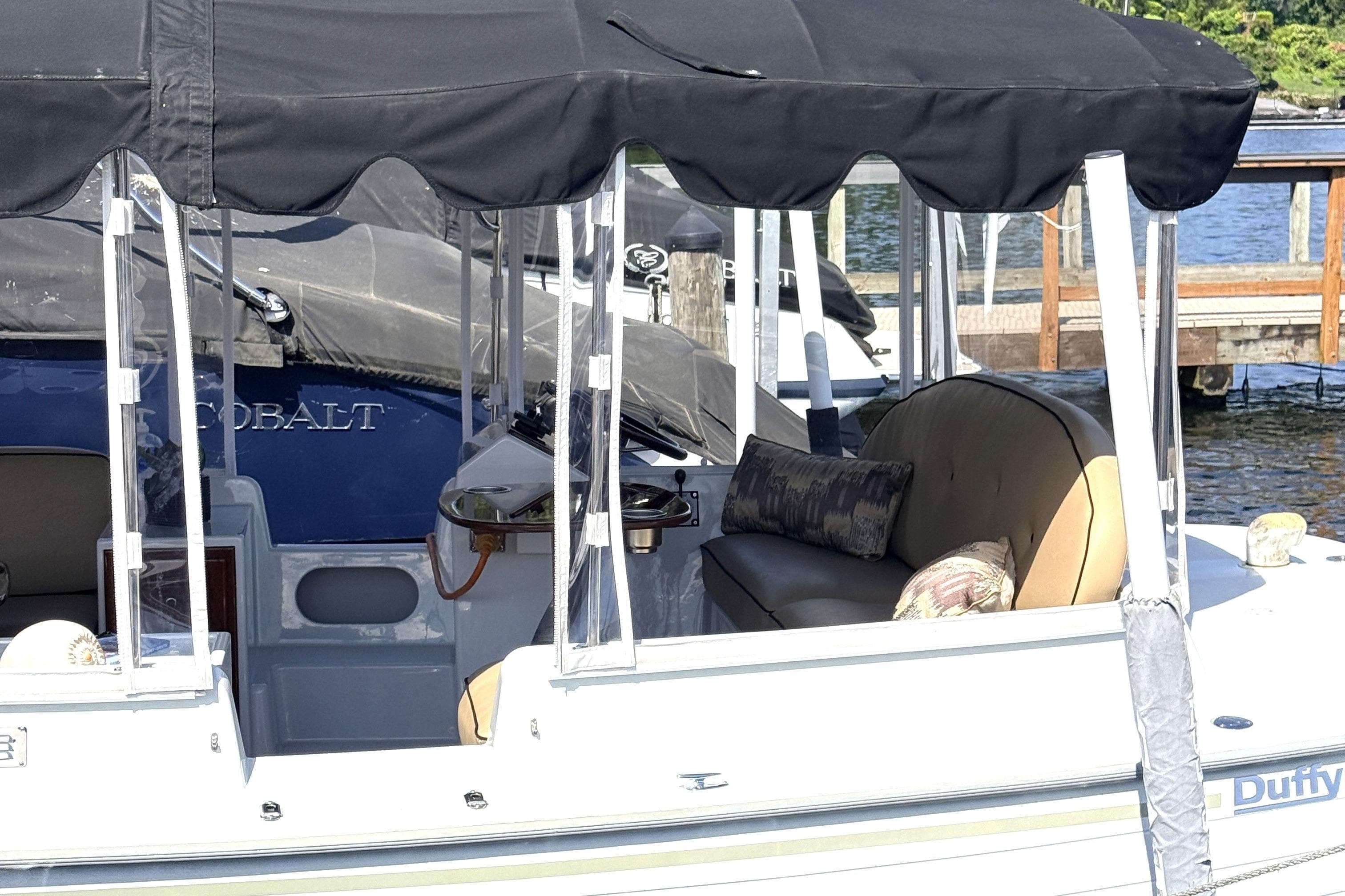 2017 Duffy Cuddy Cabin boat with canopy, docked by the water.