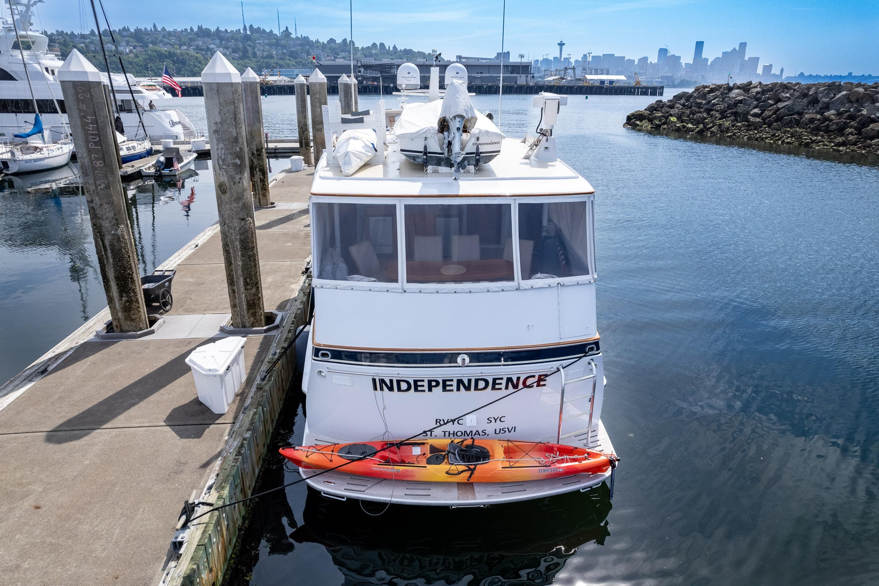 Boat "Independence" docked with kayak, city skyline in background.