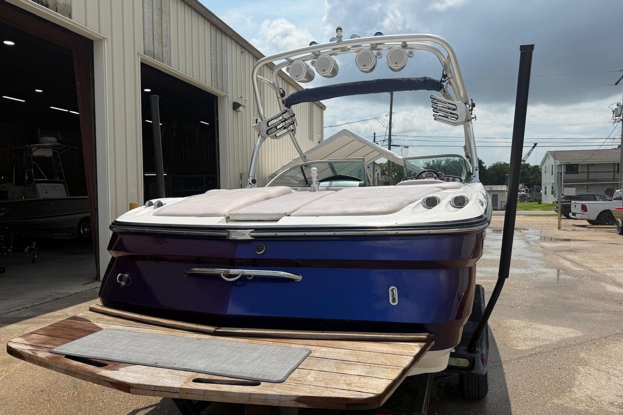 2006 MasterCraft X45 boat with blue hull, parked outside a warehouse.