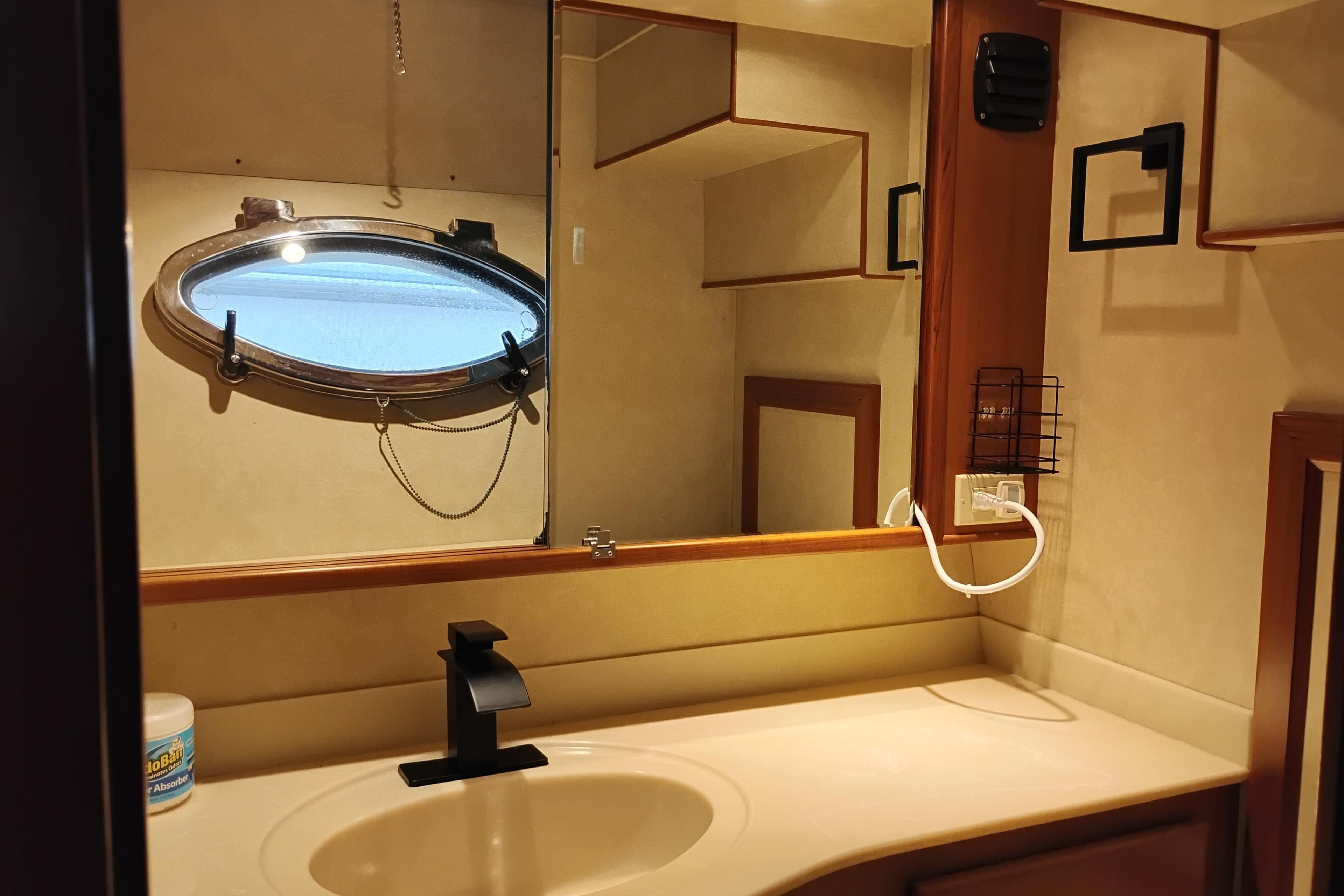 Bathroom interior of a 1997 Symbol 50 Pilothouse yacht with oval porthole window.