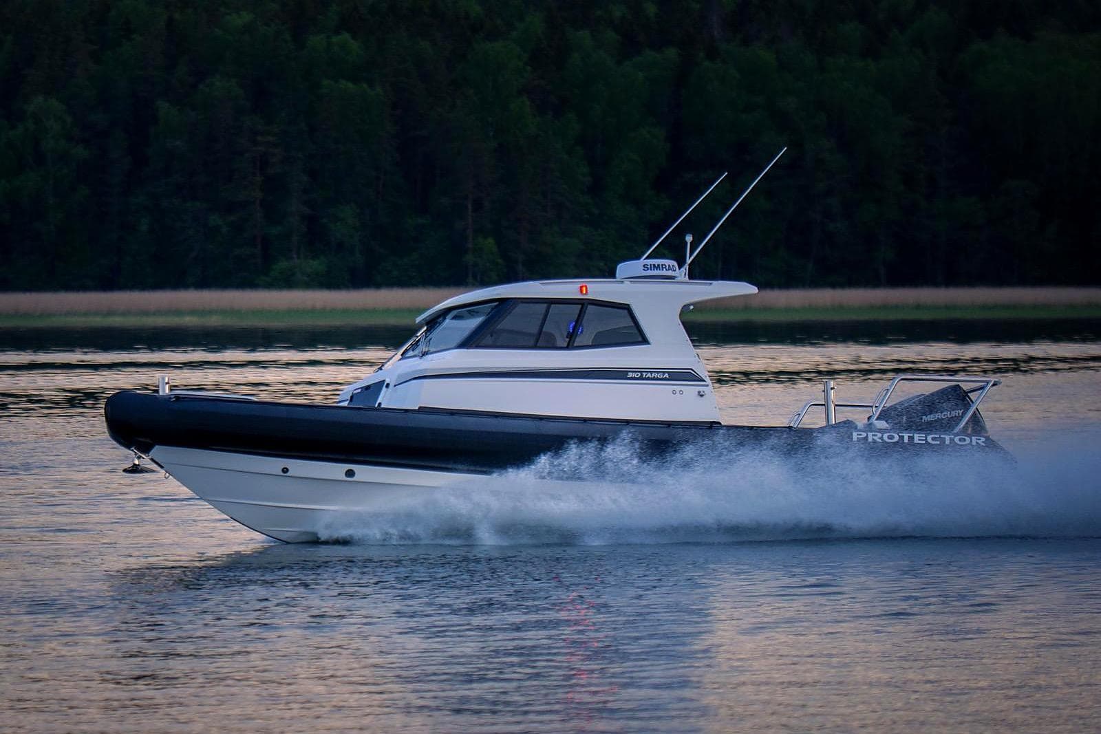 2021 Protector 310 Targa boat cruising on calm water at sunset.