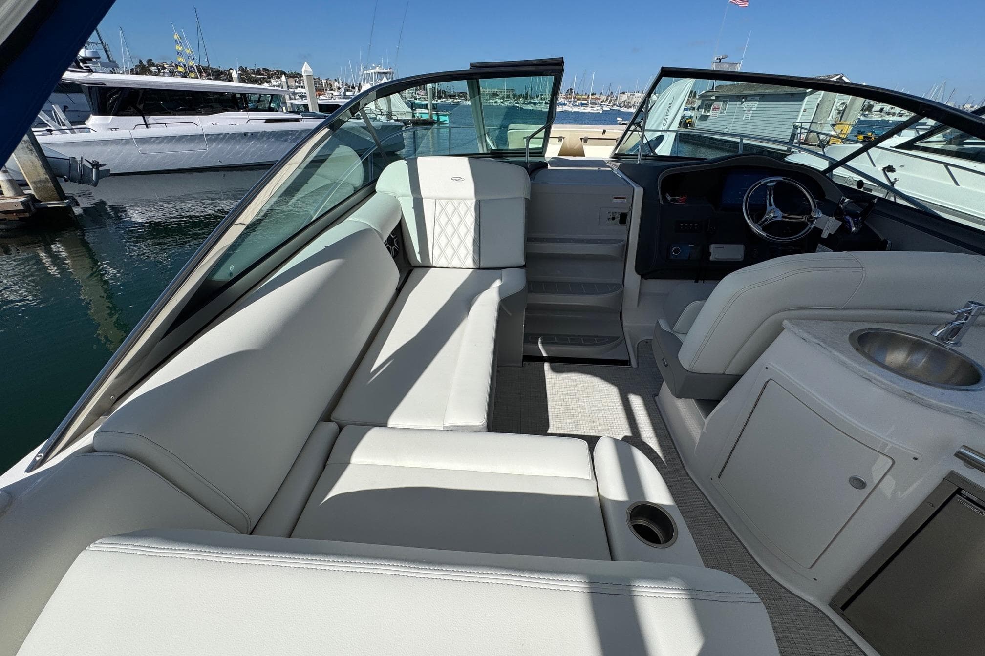 2026 Regal 33 XO boat interior with white seating, steering wheel, and sink at marina.
