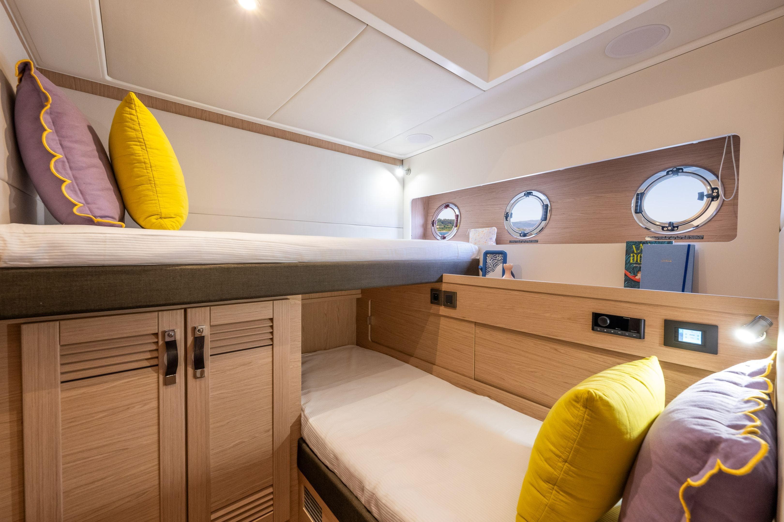 Interior cabin of 2026 Beneteau Swift Trawler 54 with bunk beds and porthole windows.
